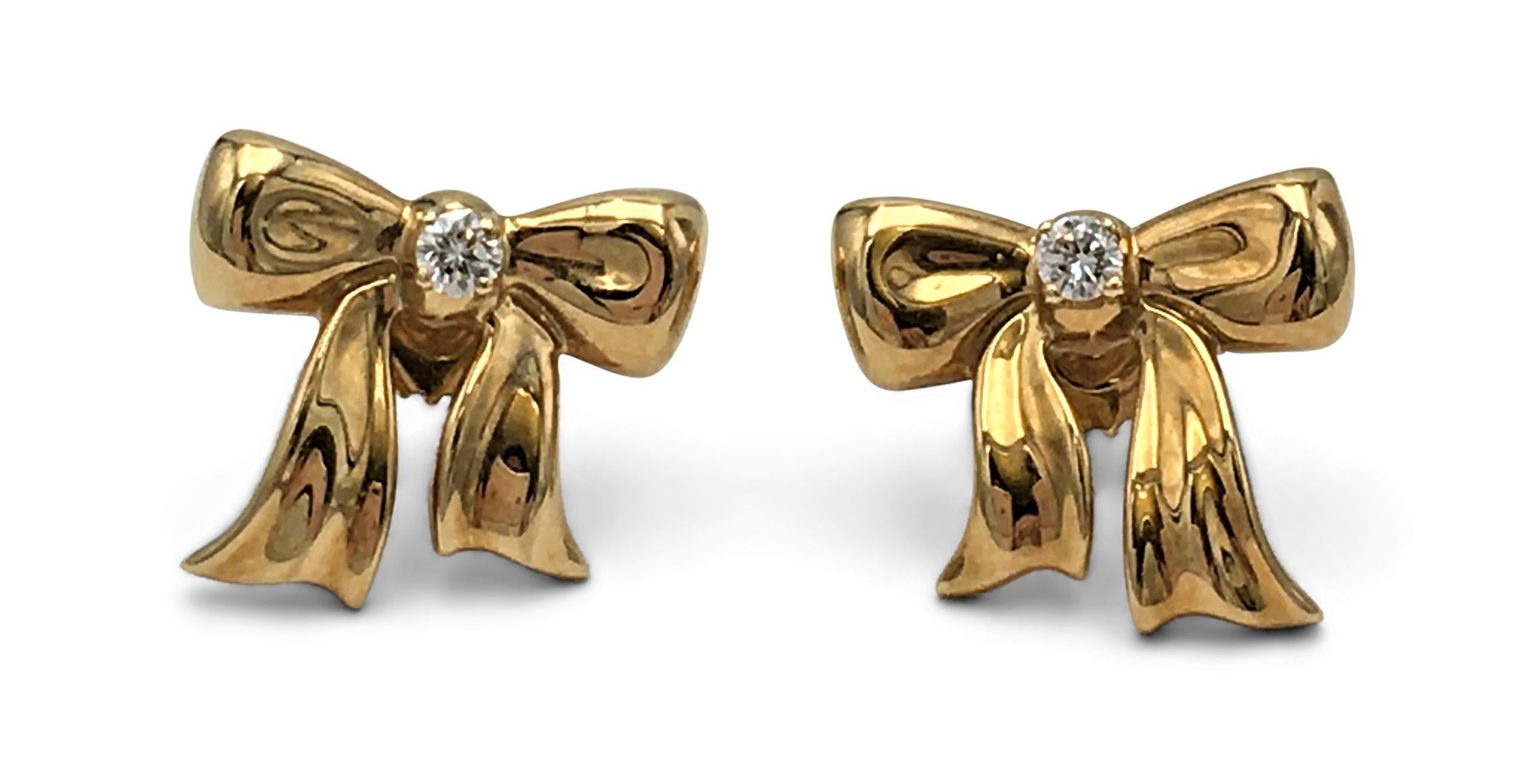 Authentic whimsical Tiffany & Co. bow earrings crafted in 18 karat yellow gold. Each bow is set with one diamond, weighing an estimated 0.05 carats. Signed T&Co., 750. The earrings are presented with the original pouch and box. CIRCA 1990s.