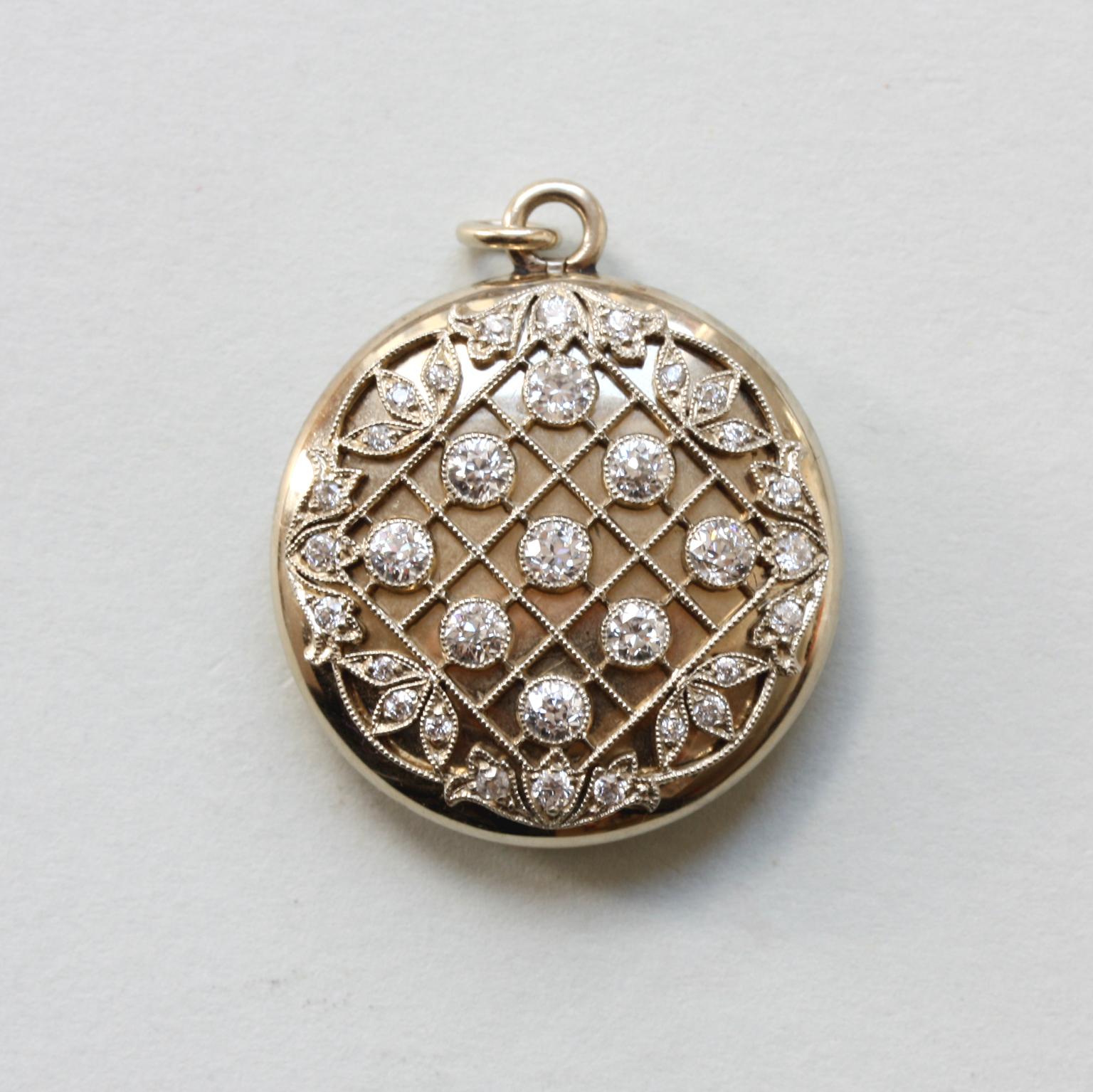 A round 20-carat gold locket with a diagonal grid with 9 mille griffe set old-cut diamonds (each app. 0.10 carat and app. 1.4 carat in total). It is surrounded by a floral border also mille griffe set with old-cut diamonds  (between app. 0.01 and