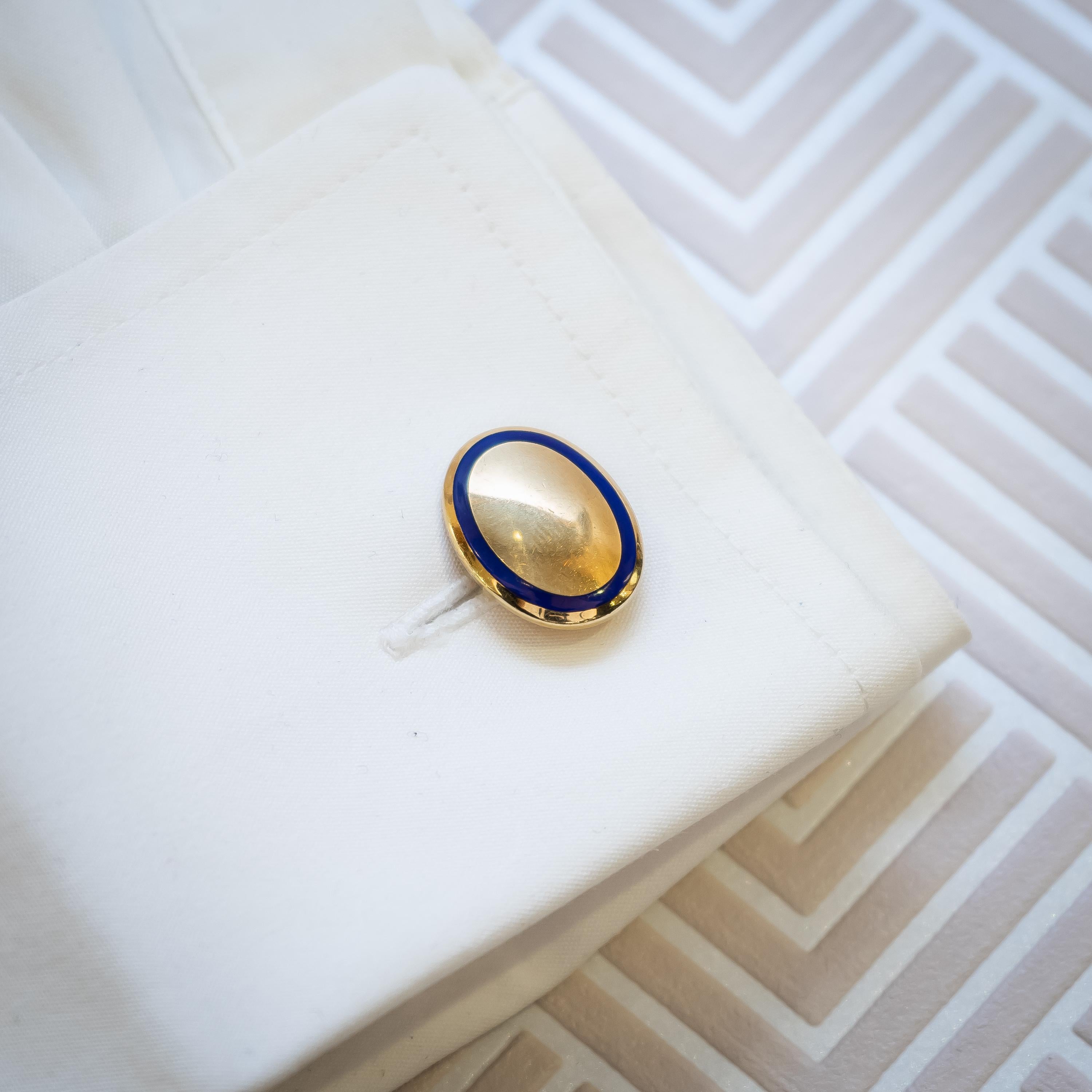 Paire de boutons de manchette en or et émail de Tiffany & Co. à tête ovale solide et concave, chacun bordé d'une bande d'émail bleu et d'un entourage d'or, montés en or 18ct, avec des ferrures à barre, signés Tiffany & Co. et T & Co, estampillés 750.
