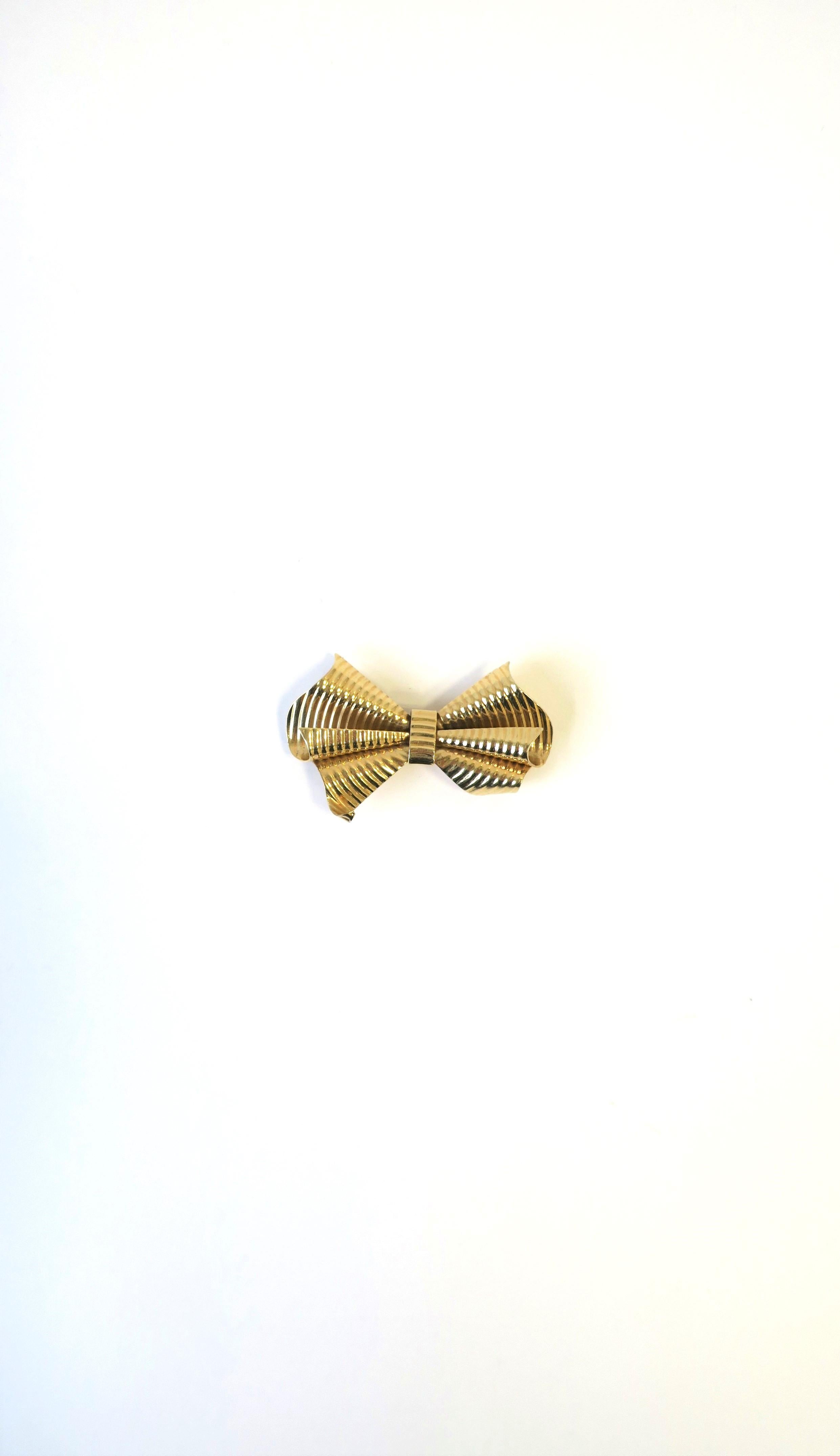 A very beautiful 14-karat yellow gold bow pin brooch from luxury jeweler Tiffany & Co. New York. Brooch is marked '14kt' on back center as shown in second to last image. Brooch is marked 'Tiffany' on pin bar on back as shown in last image. A great