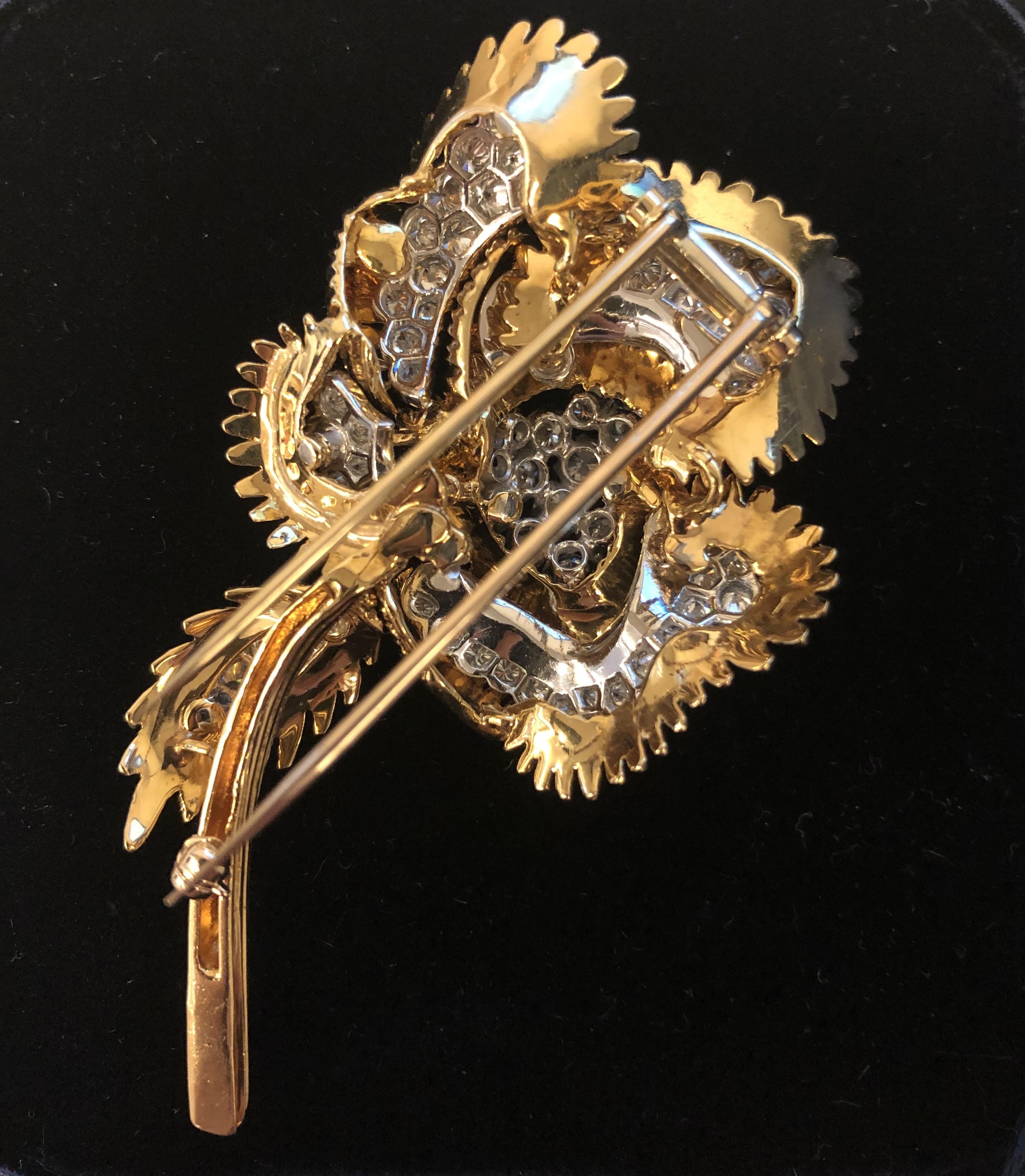 A Mid-20th Century 18 karat gold and platinum brooch with diamonds by Tiffany & Co. The flower brooch has six unique, blooming petals studded with diamonds and framed with textured gold. The piece has 73 round cut diamonds with an approximate total