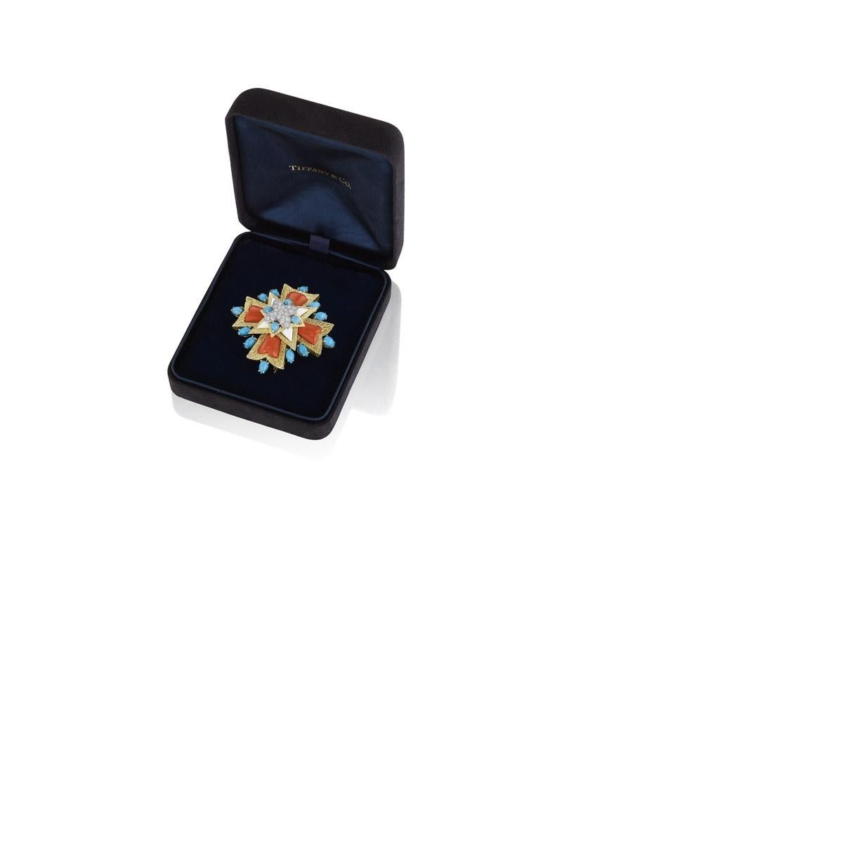 An Estate 18 karat gold brooch with coral, turquoise, enamel and diamond by Tiffany & Co. This Maltese cross, completed with engraved gold in a radiating motif, coral, white enamel and surrounded by 16 turquoise cabochons, features a centerpiece