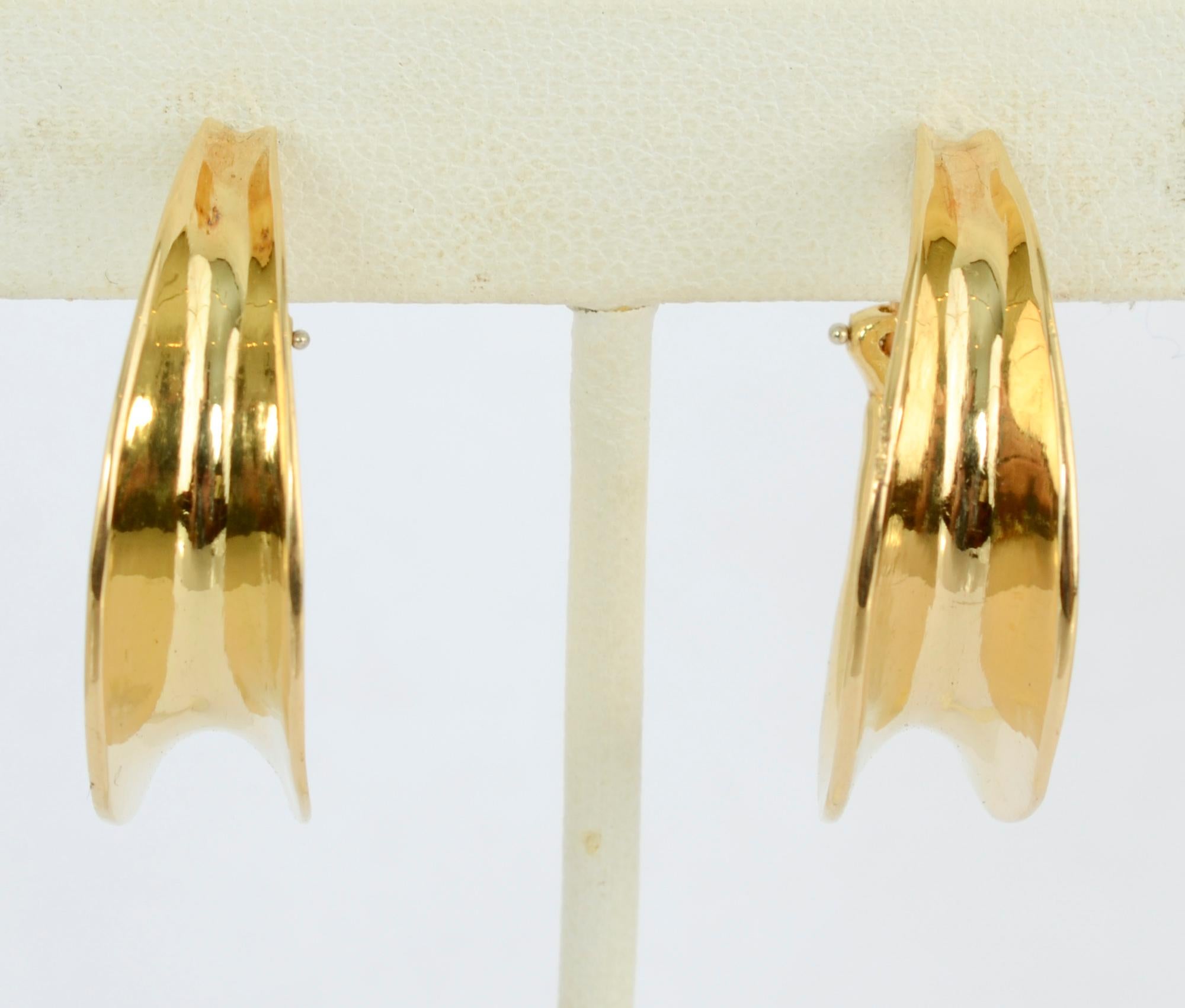 It's difficult to attribute a date to these Tiffany 18 karat gold hoop earrings because they are totally timeless in design. They are oval in shape and have concave centers. The earrings measure 1 1/8 inches in length. Backs are clips. 