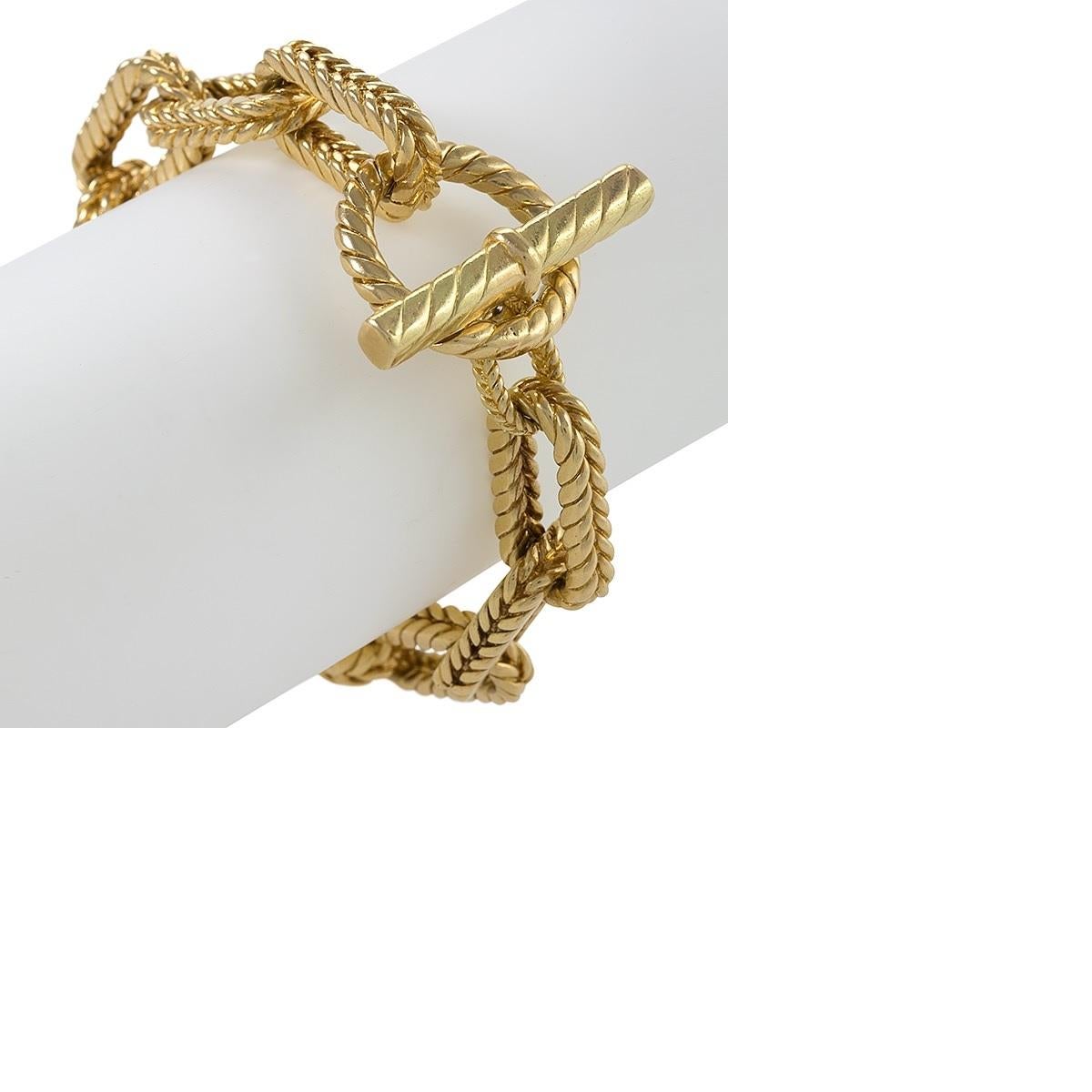 An American 18 karat gold bracelet by Tiffany & Co. The bracelet is comprised of elongated rectangularly-shaped links engraved with a design of braided rope. 
Circa 1970's.

Signed, Tiffany & Co. 750 . 