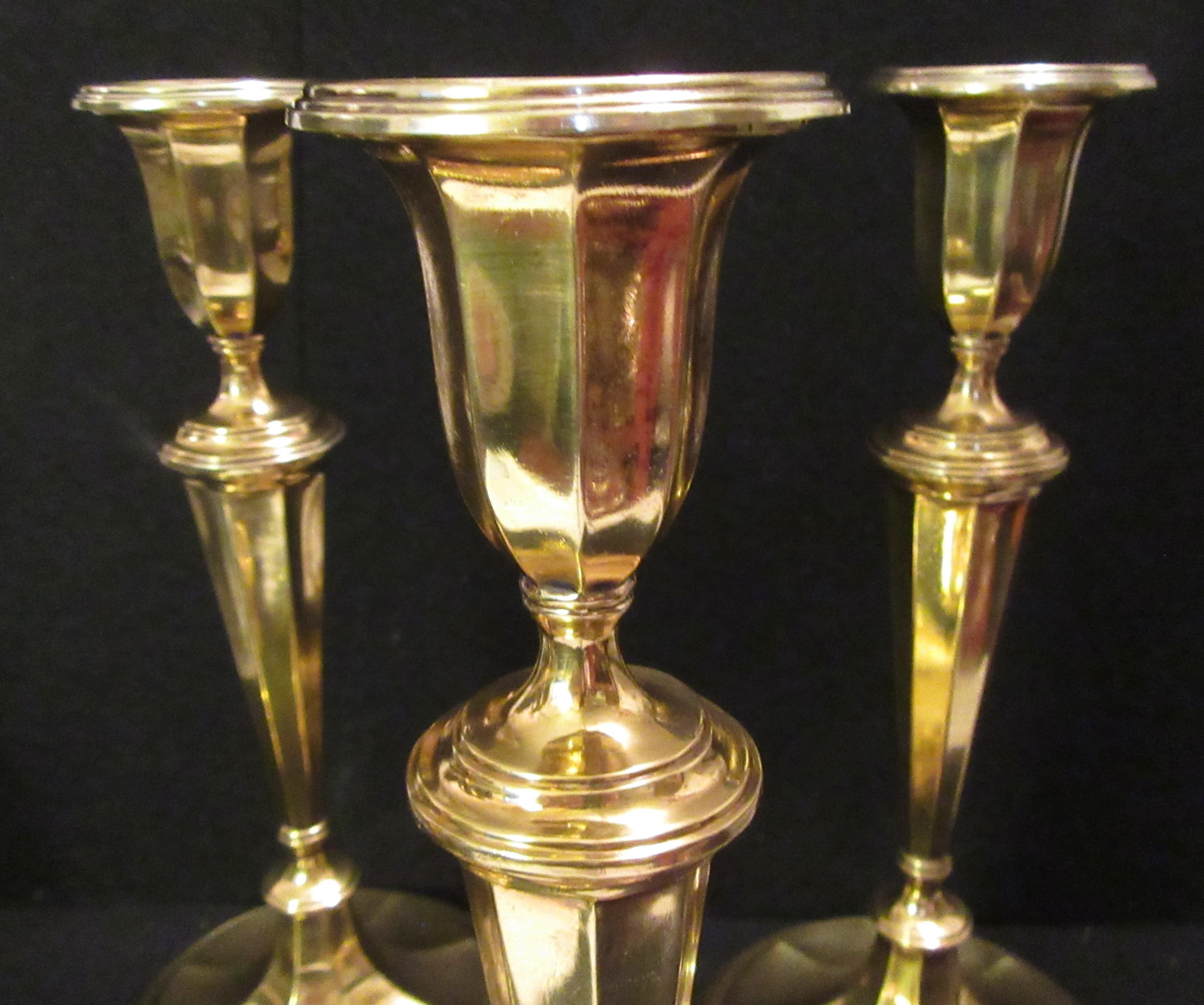 Set of four modern Tiffany & Co. gold-plated sterling silver candlesticks. Excellent condition. Made by T&Co. in England. Urn socket with detachable bobeche, tapering columnar shaft, knops, and stepped foot. Spare form embellished with reeding. The