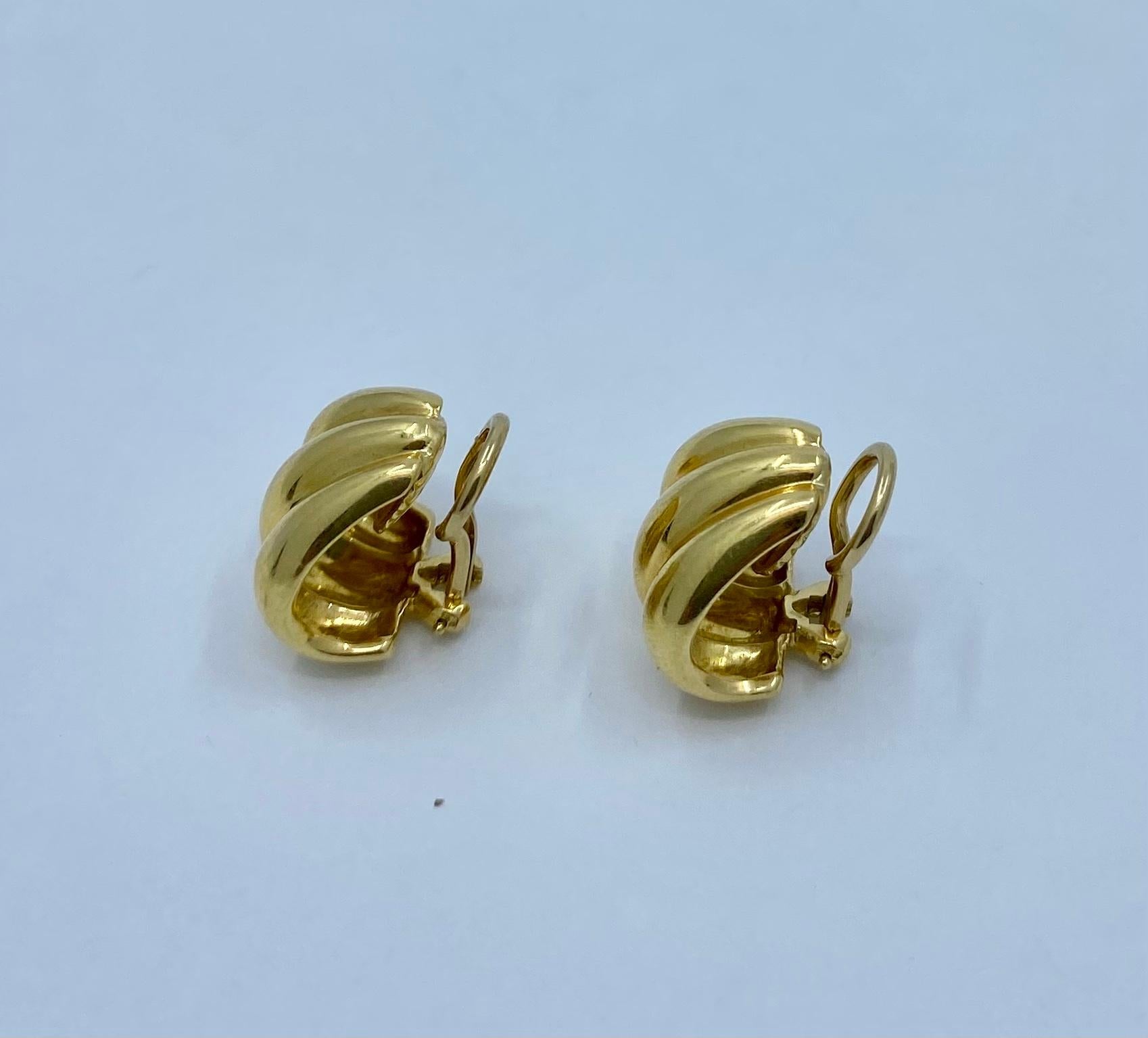 Designer: Tiffany & Co. 
Materials: 18K Yellow Gold
Weight: 10.4grams
Measurement: 9/16 inches long and 9/16 inches wide
Hallmarks: Tiffany & Co 750

A pair of Tiffany & Co. 18k gold small shell shape earrings.
The closure is clip-on.
These glossy