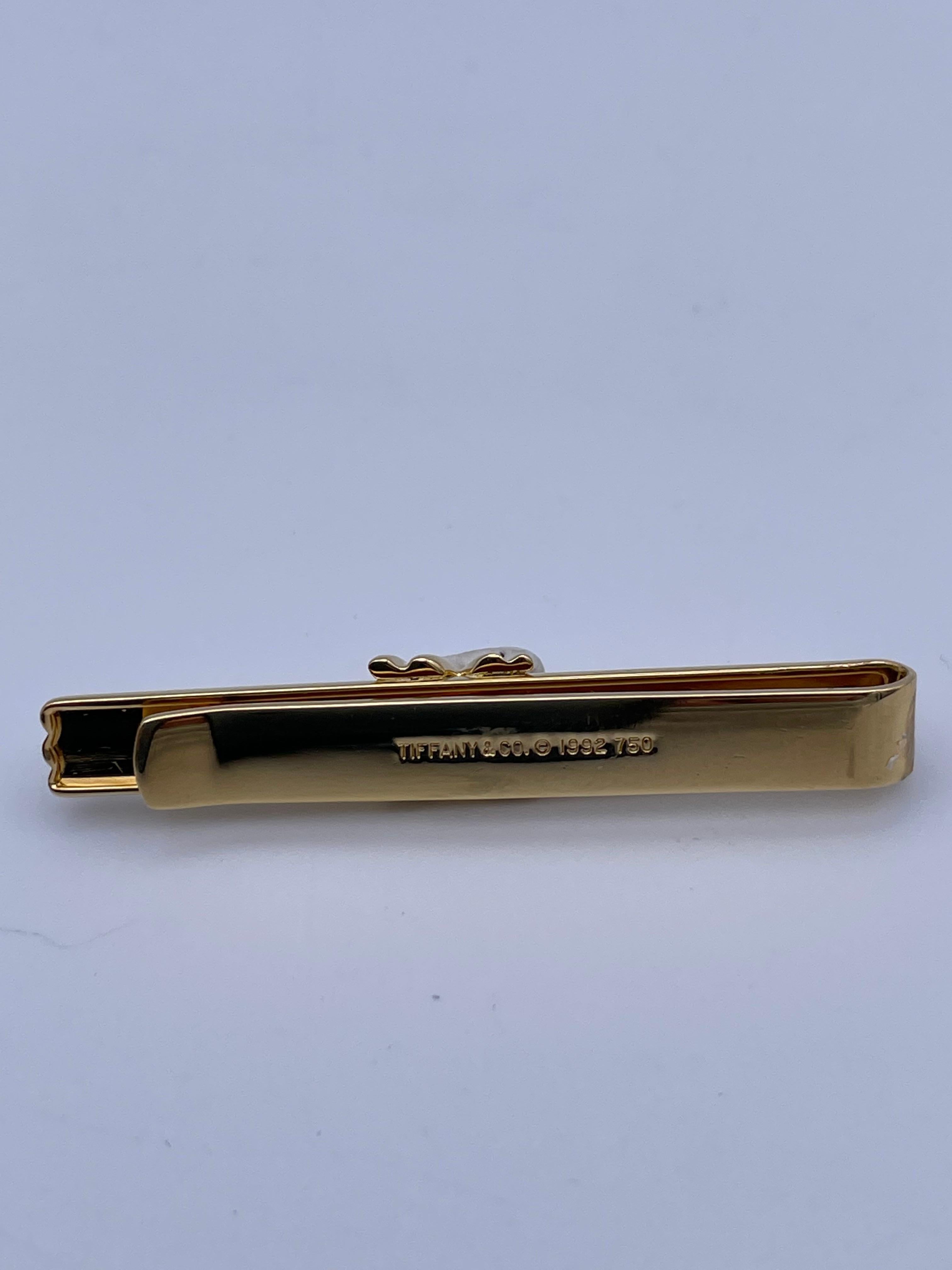 Handsome 18K yellow gold tie clip.  Made and signed by TIFFANY & CO.  Classic deep line pattern, with a raised applied 