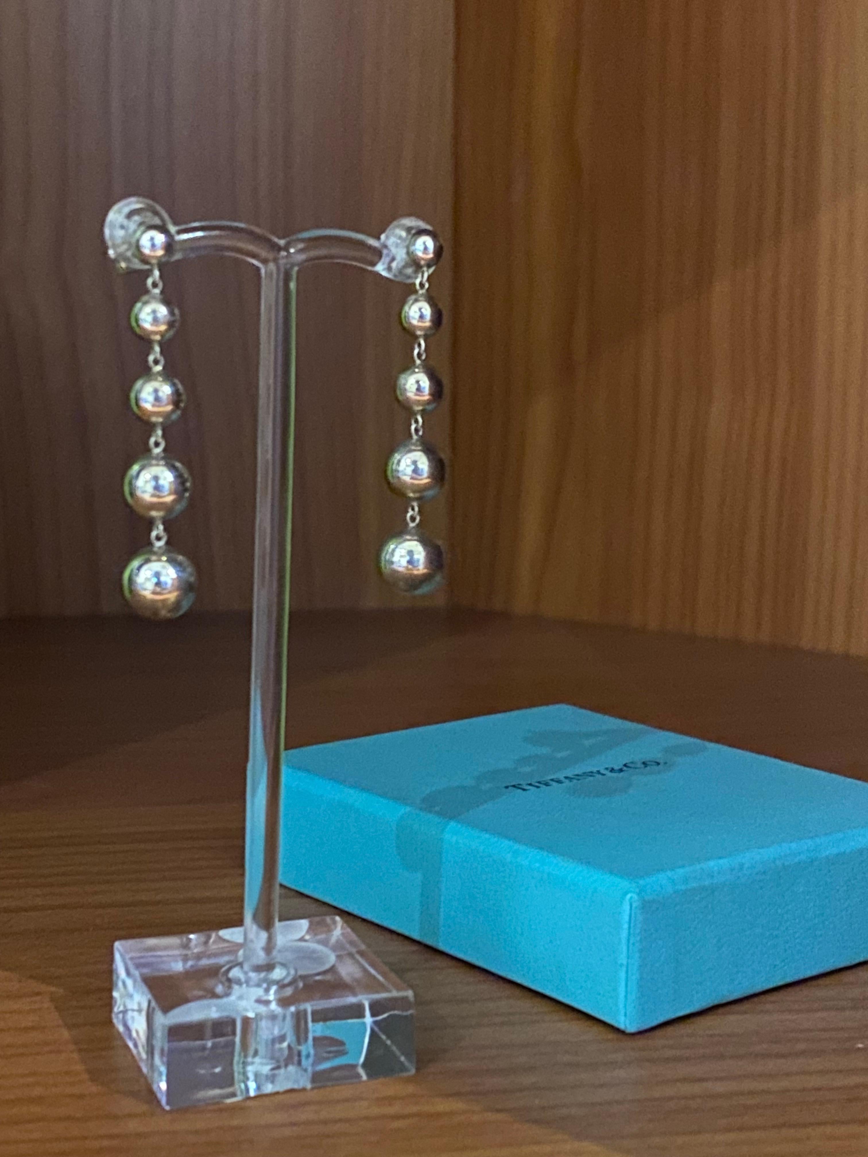 Ikonische Tiffany & Co Kugelperlen-Baumelohrringe 
aus 925er Sterlingsilber

Jedes Set mit 5 Skalenbällen
abgeschlossen durch unterzeichnete Beiträge & 
solide Schmetterlinge, 
gestempelt & gepunzt 

Länge: 40 mm 
Gesamtgewicht des Artikels: 6.6gr. 