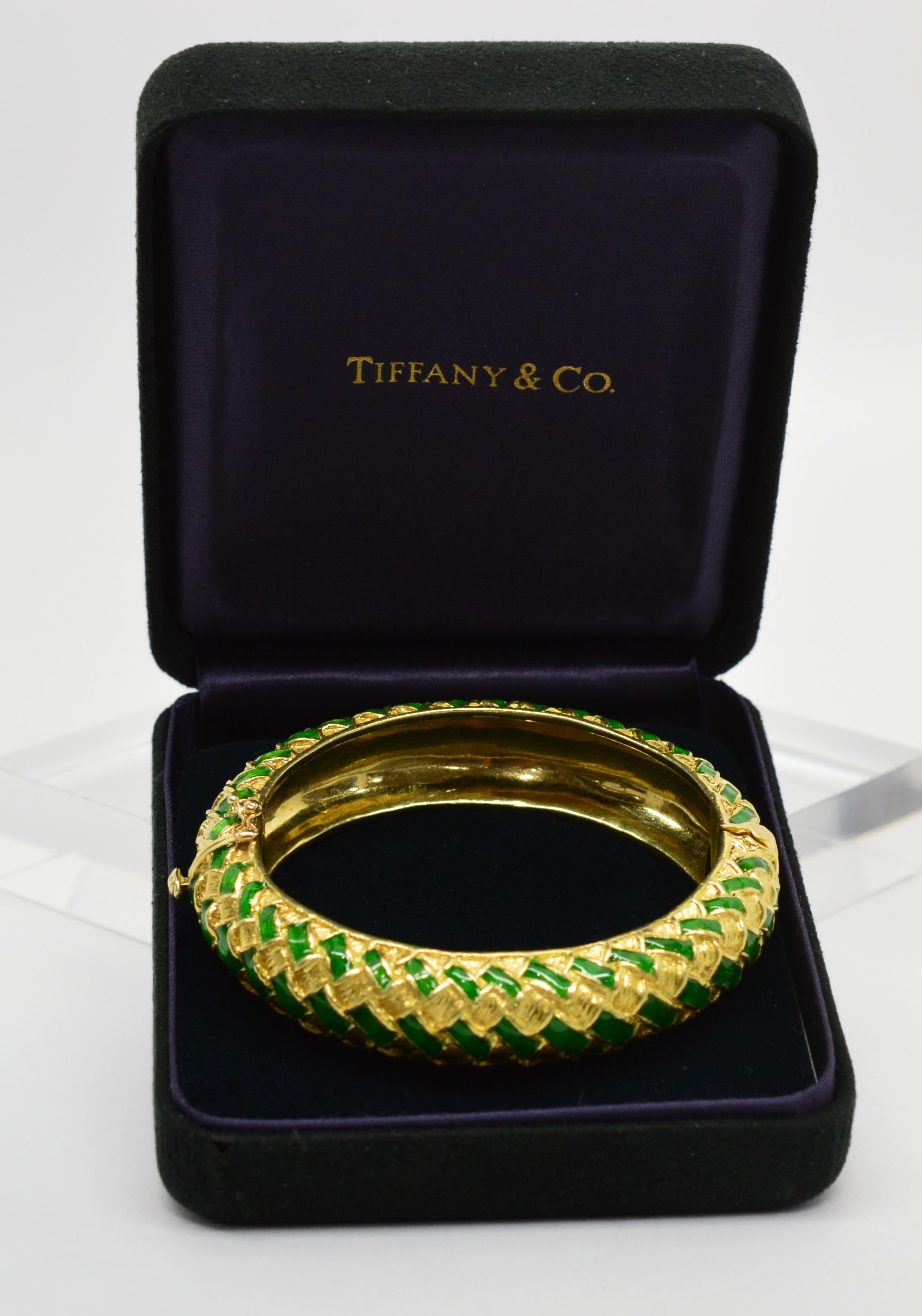 Retro 1960's and all the rage, this artfully distinctive bracelet by Tiffany & Co. integrates vibrant green enamel and bright eighteen karat 18k yellow gold to create this fabulous basket weave patterned bangle. Generously bold with a width of