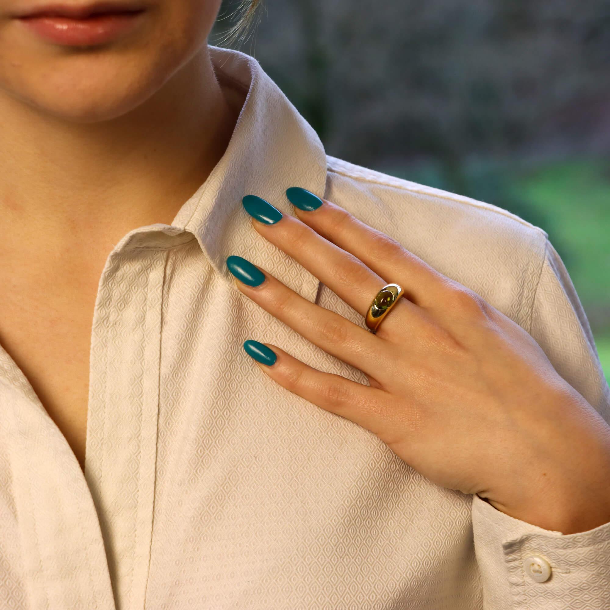 An elegant Tiffany & Co. peridot bombe ring set in 18 karat yellow gold. The piece is centrally gypsy-set with an oval cabochon green peridot which leads to a D-shape yellow gold shank. 

This ring would be perfect to wear as a statement by itself