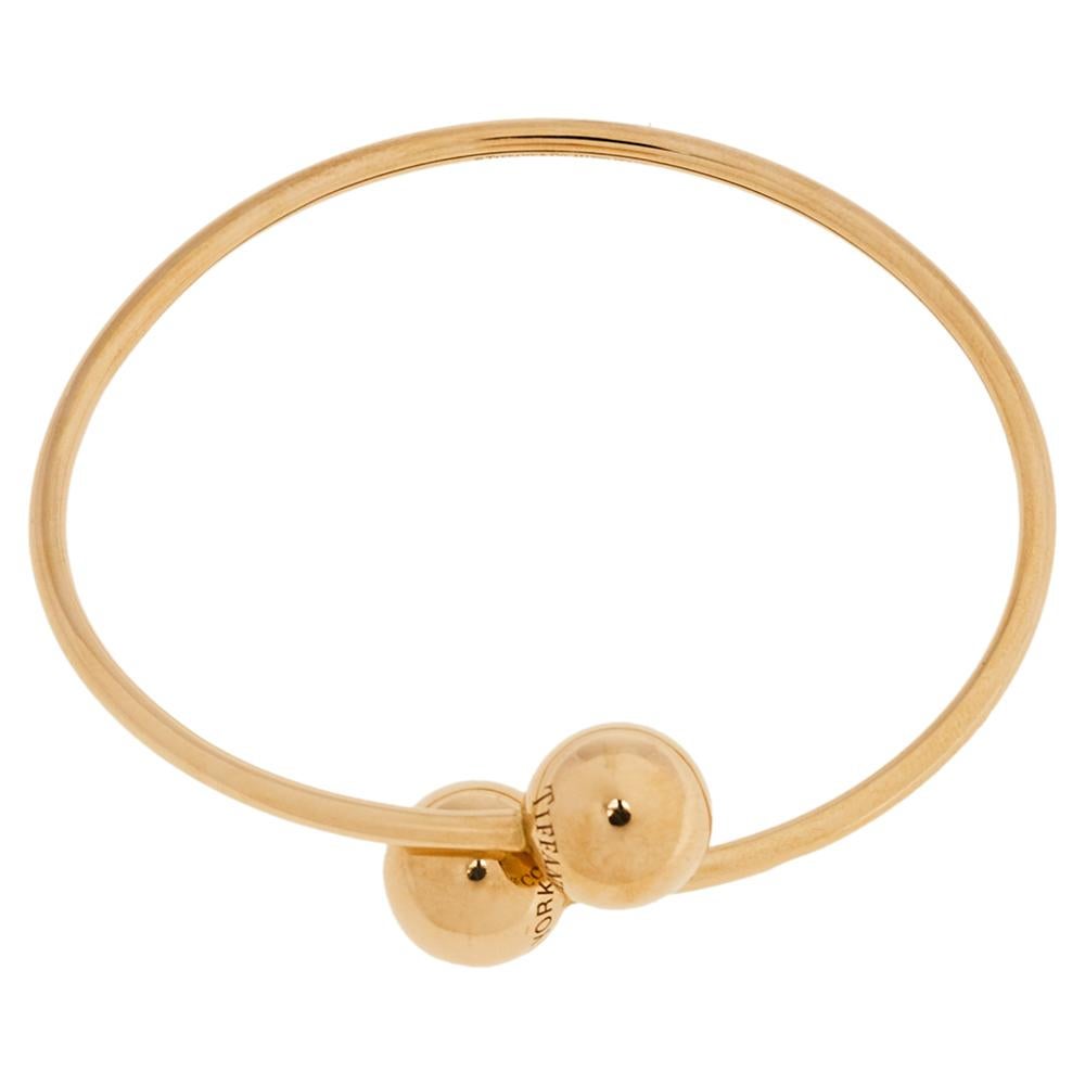 Tiffany & Co.'s spirit of innovation is well reflected in all its flawless designs. Crafted in 18K rose gold, the bracelet comes sculpted in a wire-like band punctuated with two circular motifs on its ends. It can be worn with casual or formal wear
