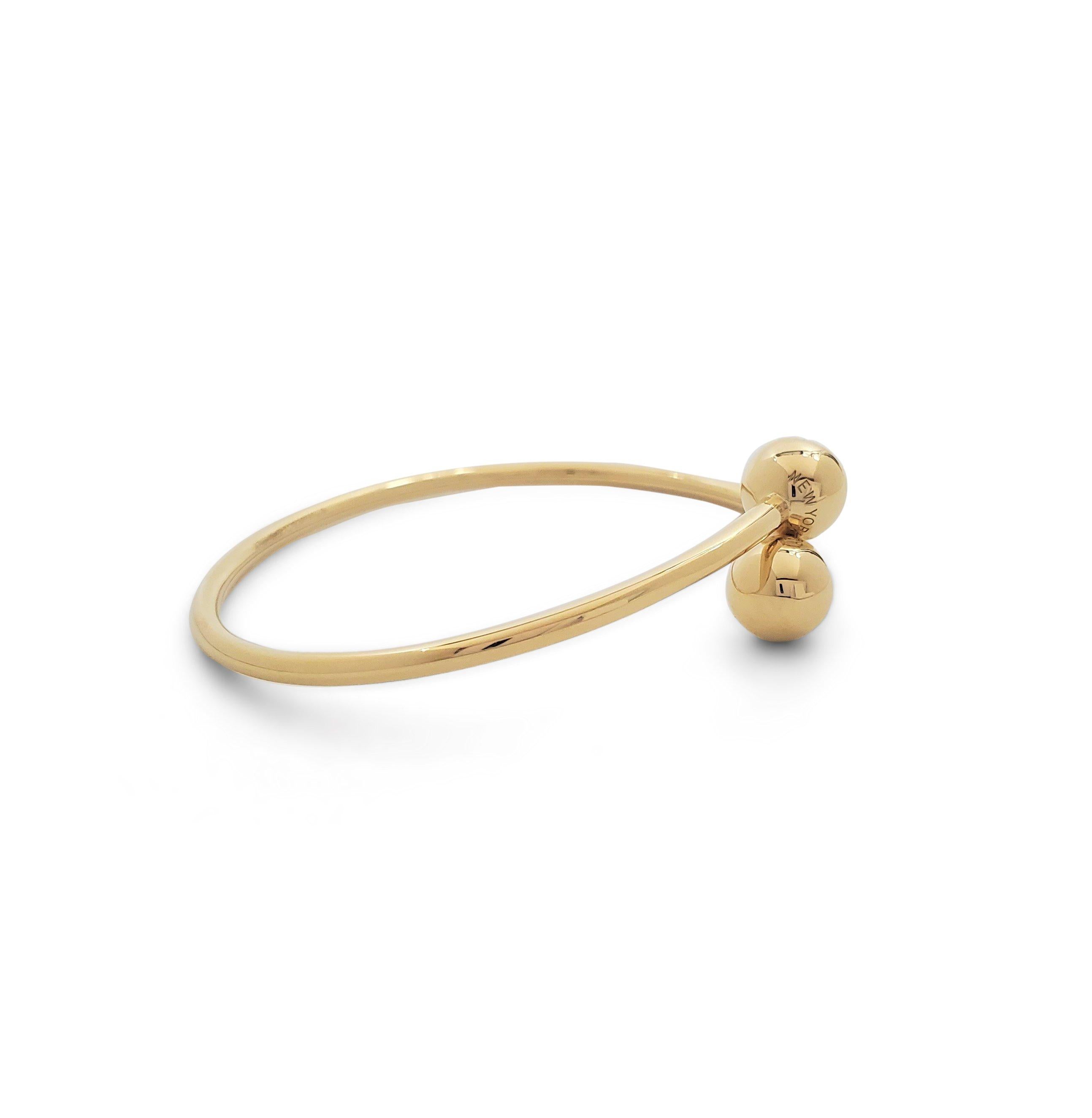 Authentic Tiffany & Co. 'HardWear Ball Bypass' bangle bracelet crafted in 18 karat yellow gold. Signed Tiffany & Co., Au750, ITALY on the base of the bangle and 'TIFFANY & CO', 'NEW YORK' on the ball ends. The bracelet is not presented with the