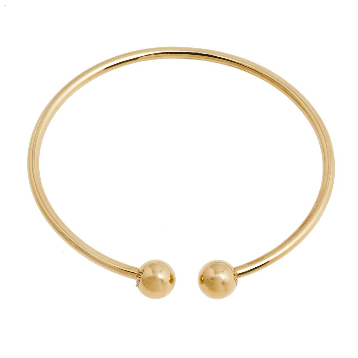 Tiffany & Co.'s spirit of innovation is well reflected in all its flawless designs. Crafted in 18K yellow gold, the bracelet comes sculpted in a wire-like band punctuated with two circular motifs on its ends. It can be worn with casual or formal