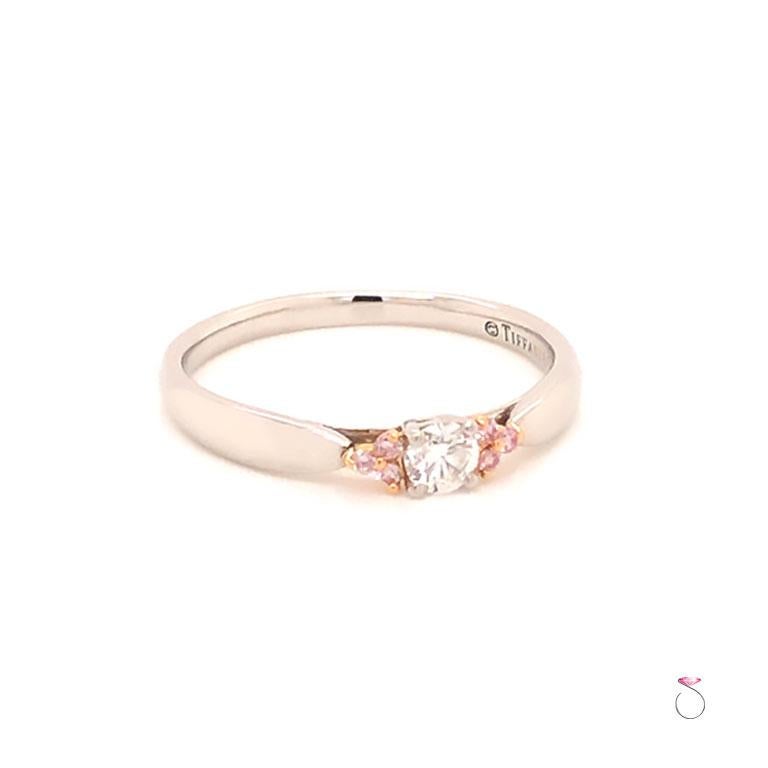 Authentic Tiffany & Co. Harmony white Diamond & Fancy Pink Diamond Side Stone Ring in platinum & 18K rose gold. Elegantly framed by six Fancy Pink diamonds in 18k rose gold, a round brilliant white diamond glows in platinum. White diamond, carat
