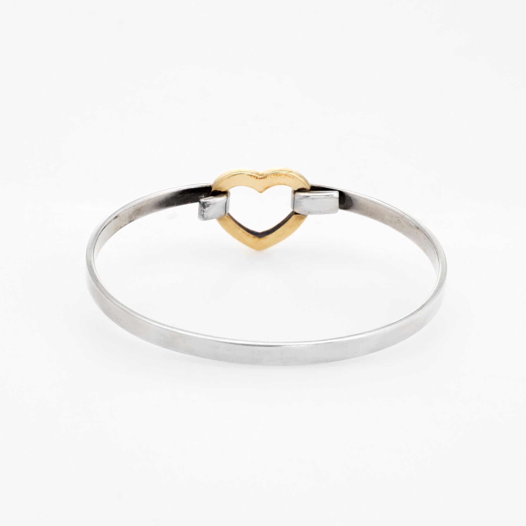 Elegant pre owned Tiffany & Co heart bangle bracelet, crafted in 18k yellow gold and 925 sterling silver. 

Circa 2003 the heart is comprised of 18k yellow gold with the body of the bracelet crafted in sterling silver.  

The bracelet is in