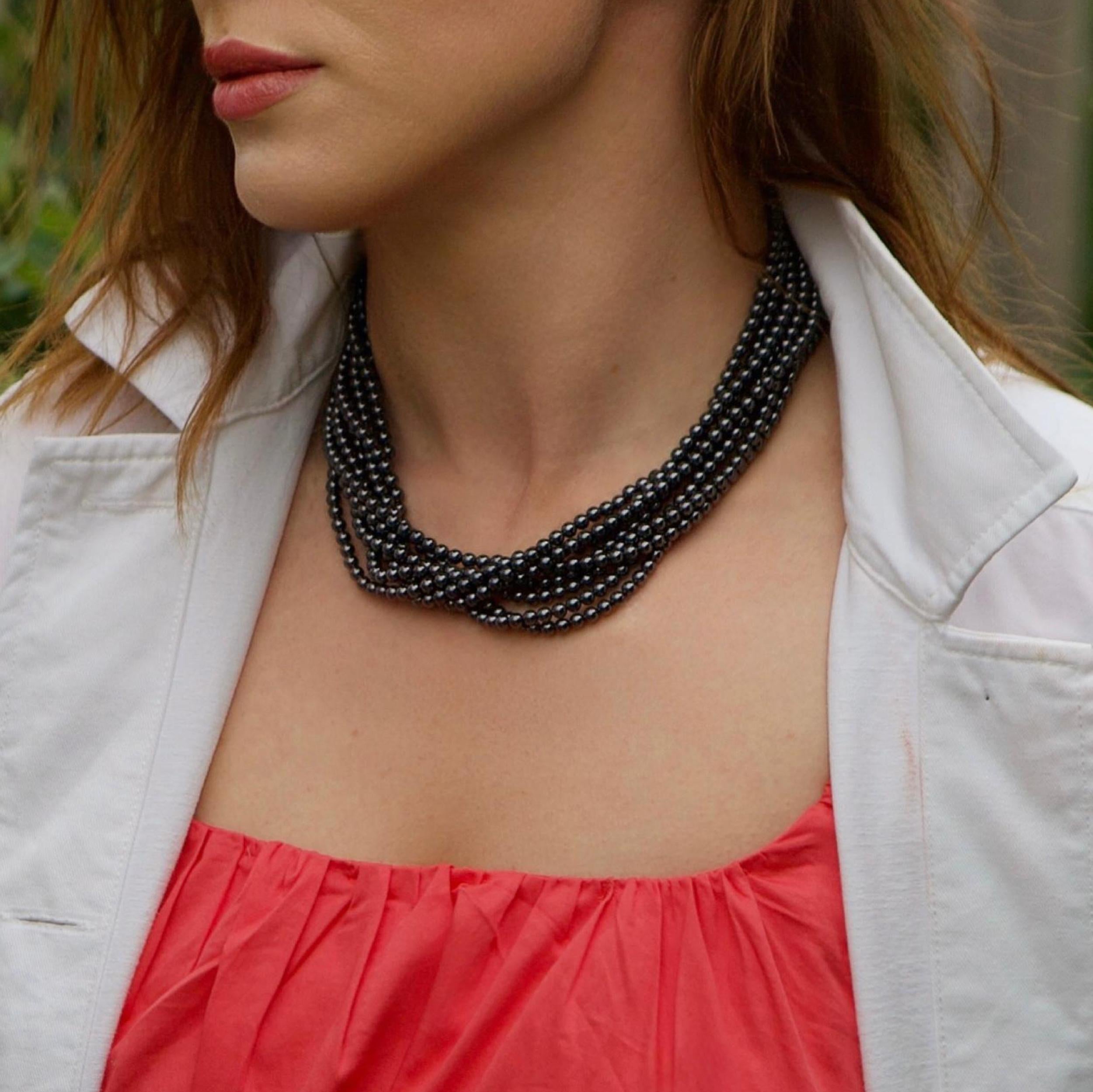 A bold and elegant necklace by Tiffany & Co., composed of eight strands of polished, round hematite beads, culminating in a signature twisted sterling silver toggle clasp. This sculptural torsade design sits beautifully on the neckline with a fluid