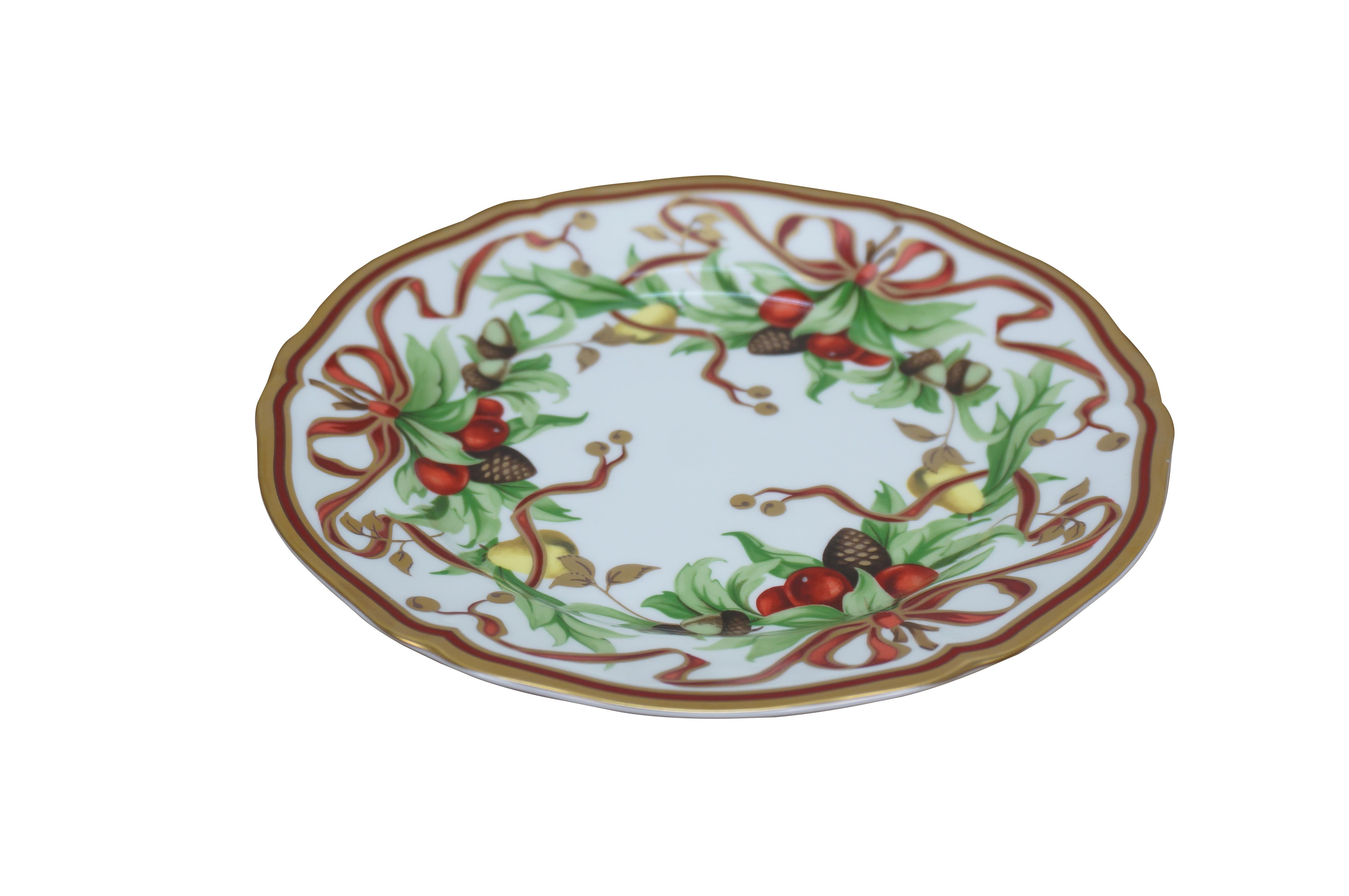 Single Tiffany & Company Tiffany holiday bread and butter plate. White porcelain with gilded scalloped edge, decorated with a Christmas themed garland of holly, pine cones, pears, and acorns, tied with bows of red and gold ribbon.

Dimensions:
7.75