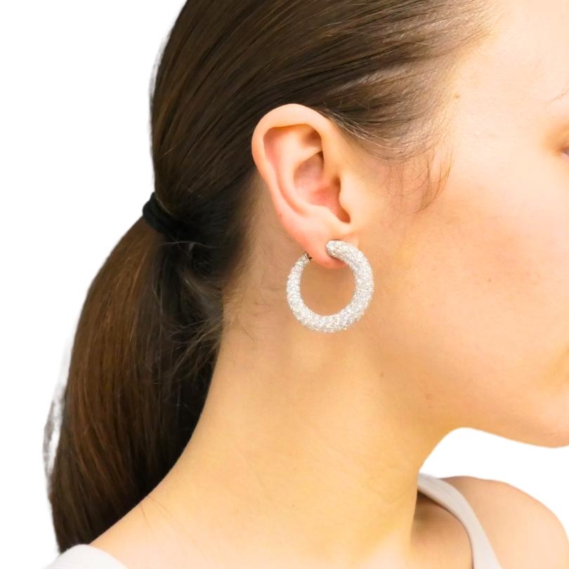 A dazzling pair of Tiffany & Co. hoop earrings made of platinum, featuring diamonds.
These Tiffany hoop earrings are generously set with diamonds, covering the entire surface and creating a continuous shimmer from every angle. The platinum setting,