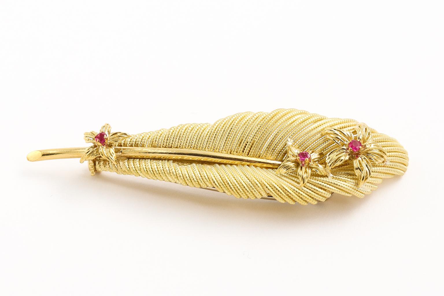Vintage pin made by Tiffany & Co. It is the classic feather style. The pin is 15 grams although it has the airy feather look. 2 5/8 inches long with three rubies in the center of azaleas. Marked Tiffany & Co., 18 Kt, Italy on the back. The box and