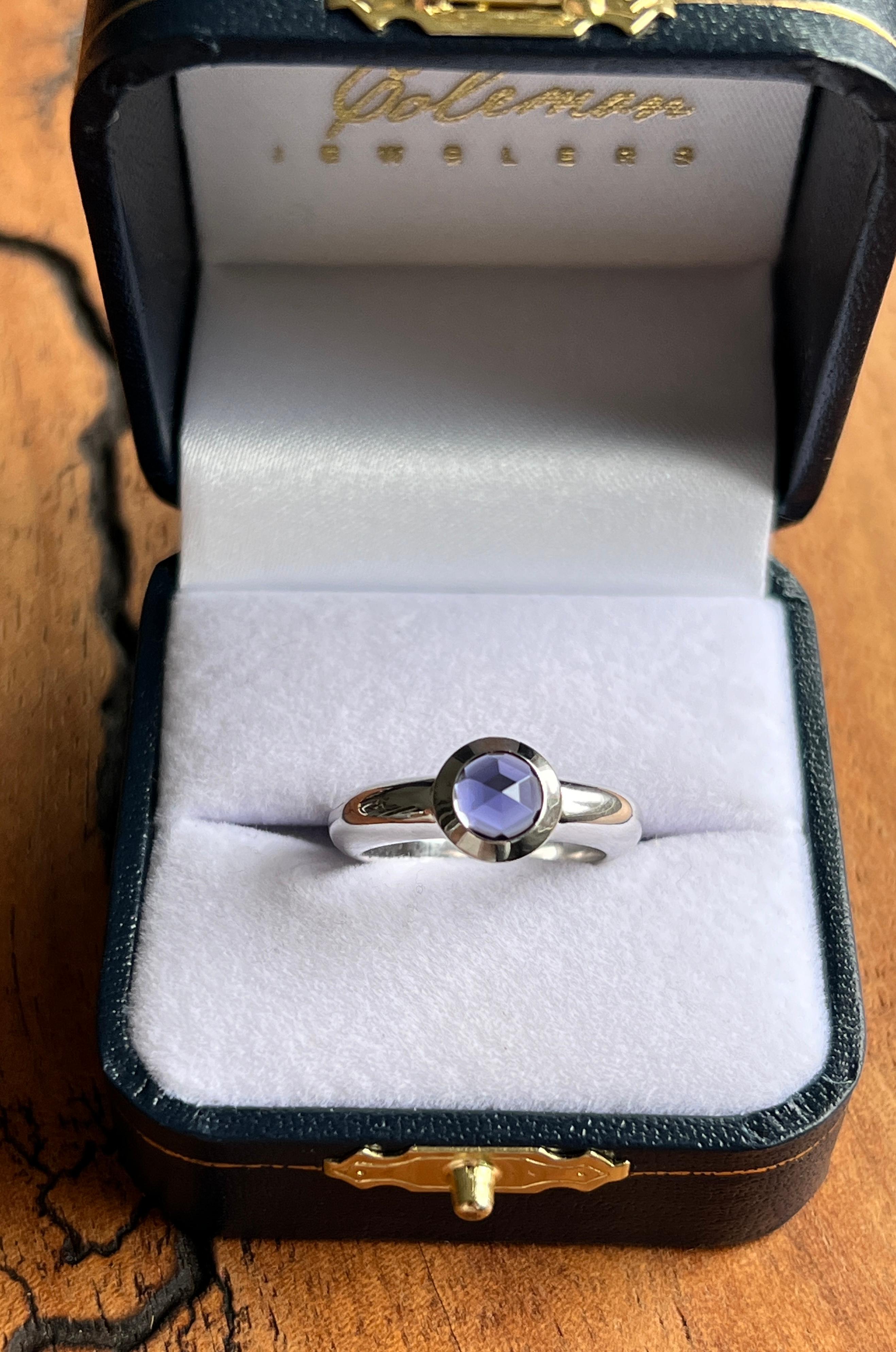 Une bague contemporaine de Tiffany & Co. en or blanc 18 carats, ornée d'une Iolite ronde de 6 mm de diamètre taillée en rose et pesant environ 0,73 carats, sertie d'un chaton. La pierre précieuse présente une riche teinte bleu-violet, magnifiquement