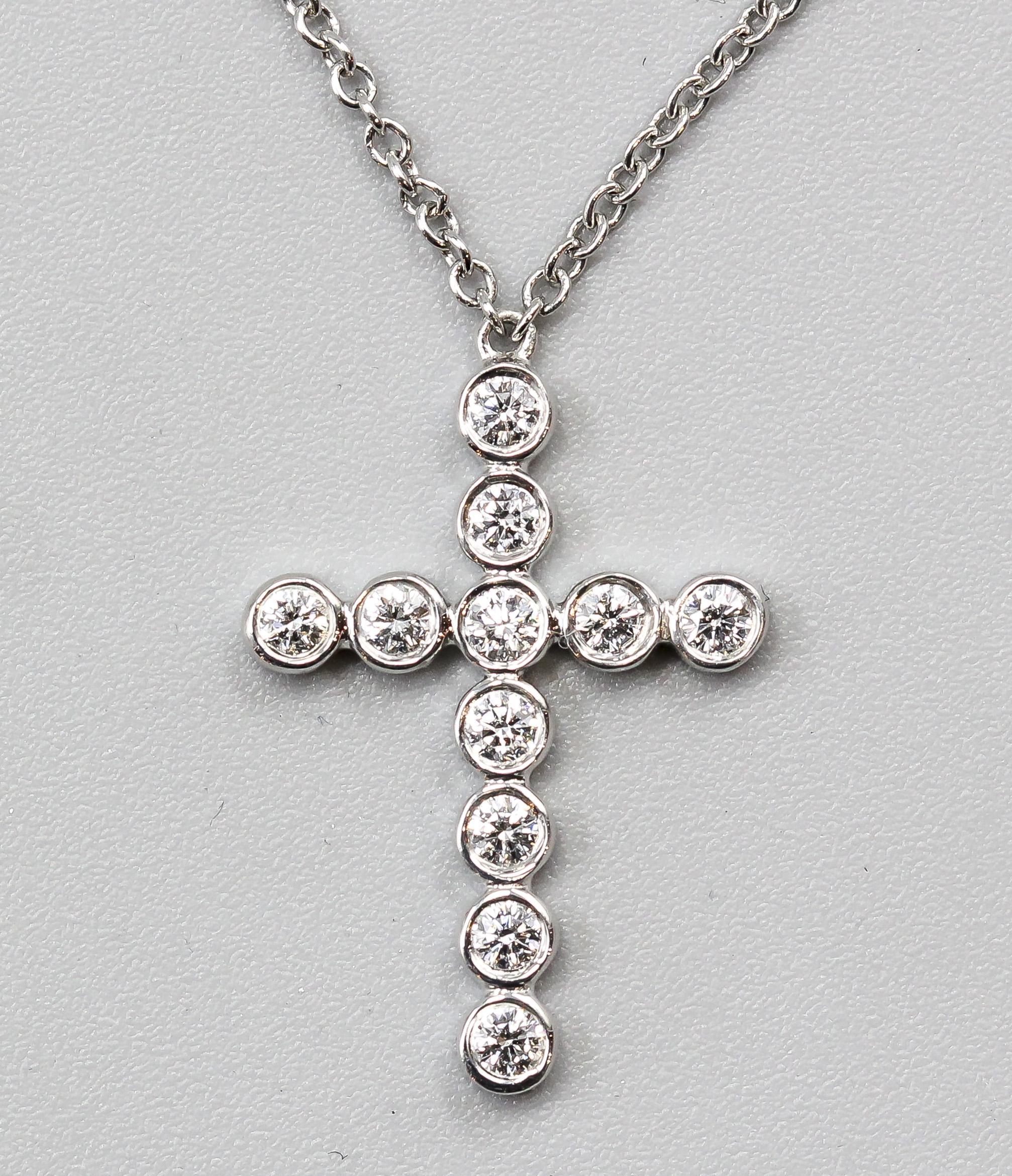 The Tiffany & Co. Jazz Bezel Set Diamond Platinum Cross Pendant Necklace is a stunning and graceful piece of jewelry that showcases the brand's dedication to exquisite craftsmanship and timeless design. This pendant necklace is a work of art,