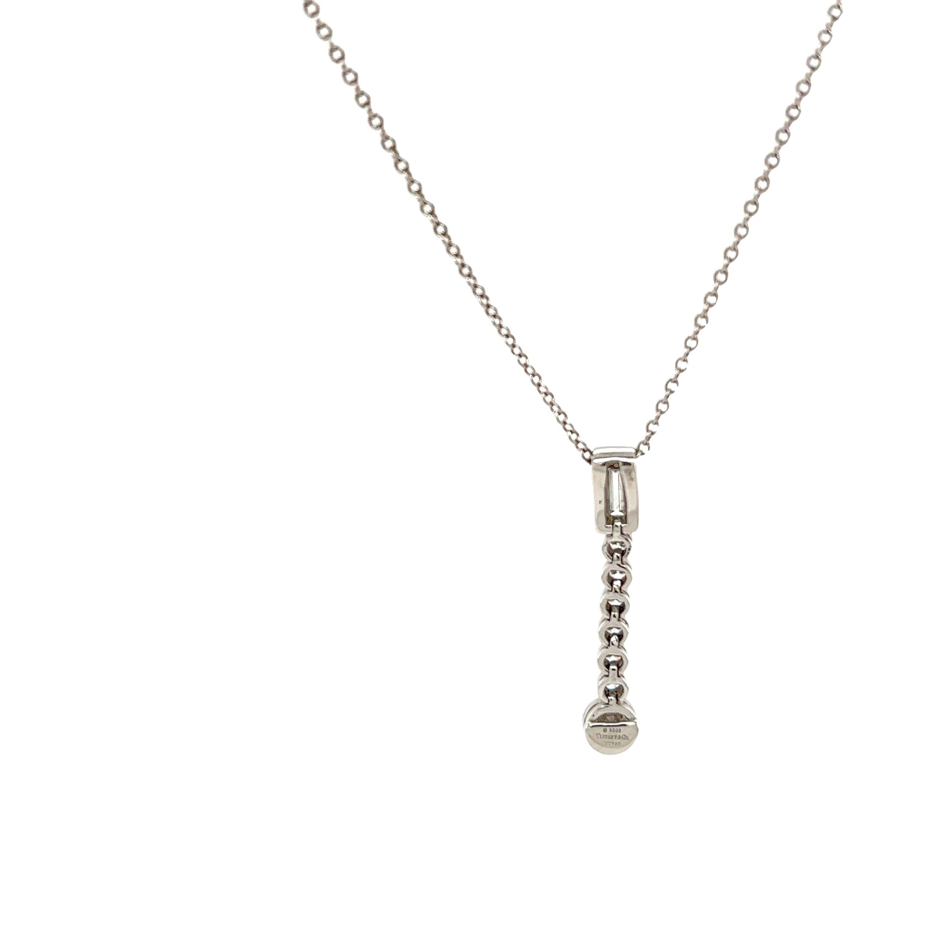Embrace timeless elegance with this Tiffany Jazz diamond drop pendant, where luxury meets simplicity. Suspended on a delicate platinum chain, the linear progression of 7 round diamonds and 1 emerald cut diamond leads to a captivating centerpiece