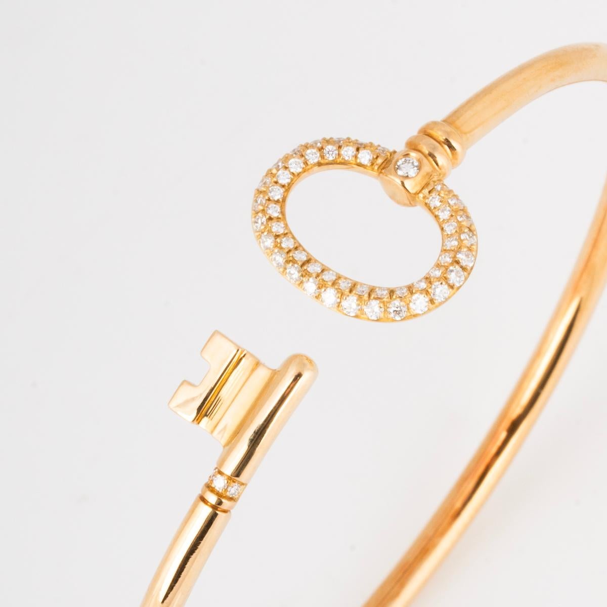 An 18k yellow gold diamond wire bracelet from the Tiffany Keys collection by Tiffany & Co. The bracelet is in the form of a key wrapped around the wrist with round brilliant cut diamond set to the head and tip, totalling 0.18ct. The bracelet