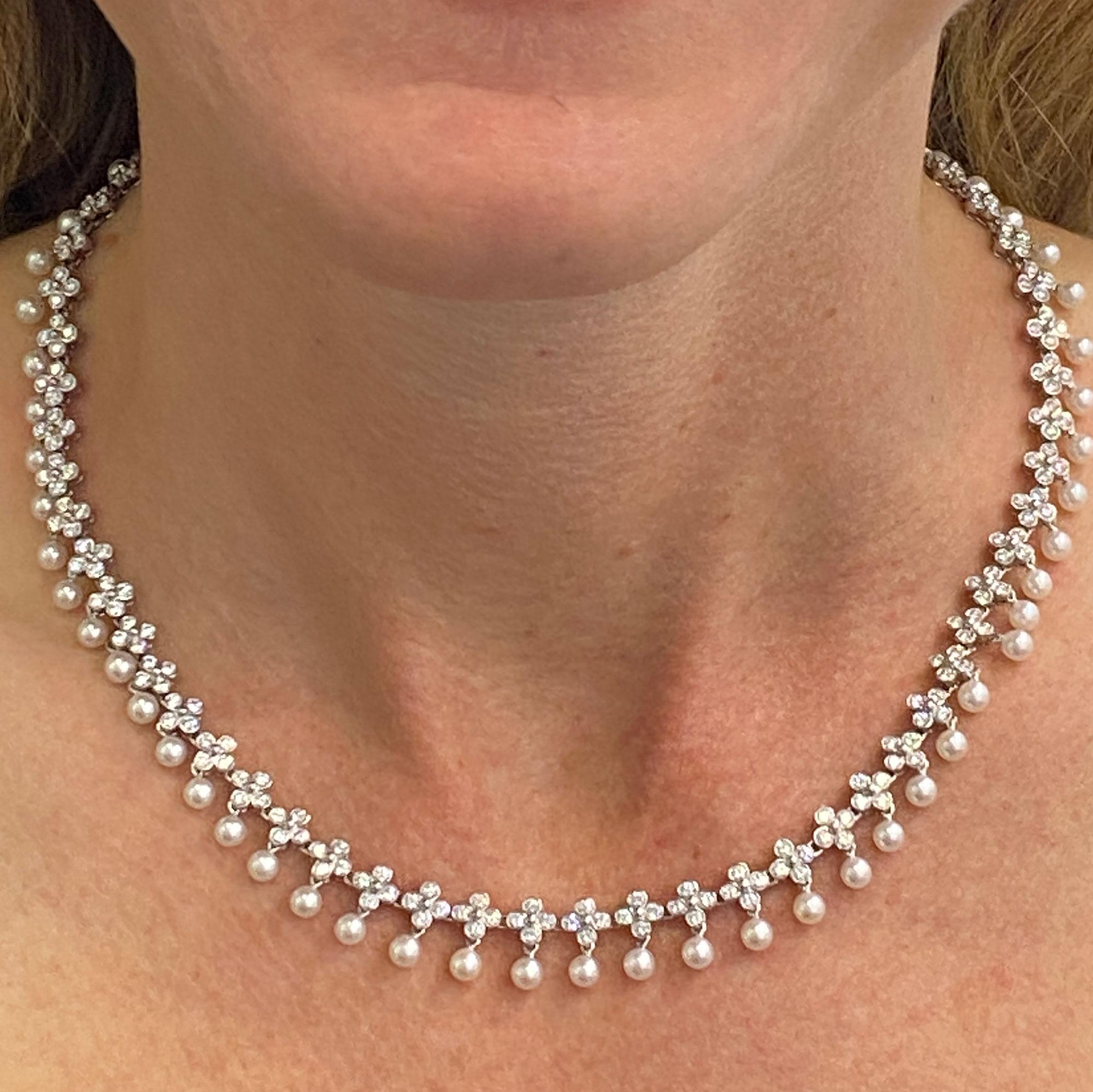 Elegant diamond and pearl drop necklace designed by Tiffany & Company. The Lace diamond necklace circa 2012 is comprised of platinum, diamonds, and pearls. Measuring 3/8 of an inch wide, each link is comprised of a clover of four round brilliant cut