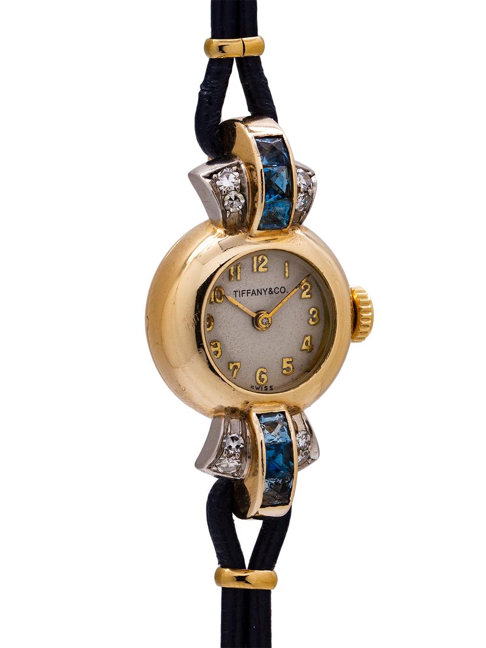 Vintage lady’s Tiffany & Co. 14K YG dress watch circa 1940’s. Beautiful design model with small distinctive dome shaped Cressarrow signed case and extended, curved triple pronged lugs, set with diamonds and sapphires. With contemporary cord leather