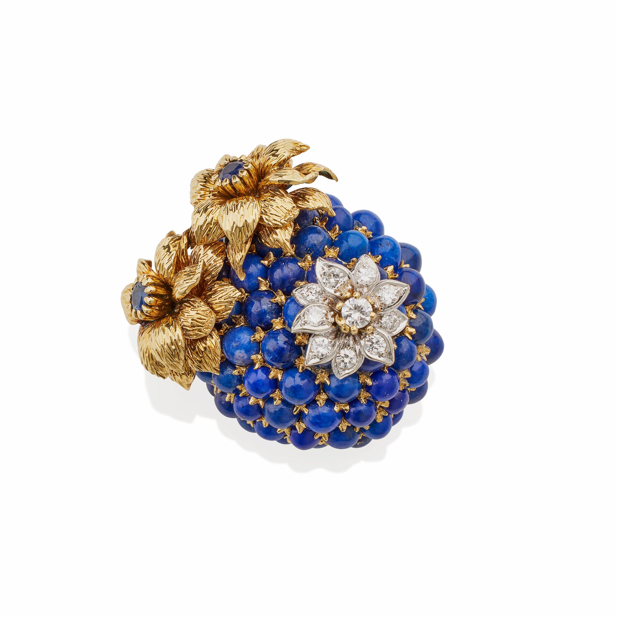 Created in 1968-1969, this Tiffany & Co. brooch is composed of bi-color 18K gold, lapis, and diamonds. It is designed as blue blossom or berry set with lapis lazuli cabochons, surmounted with a diamond floret and two gold florets accented by