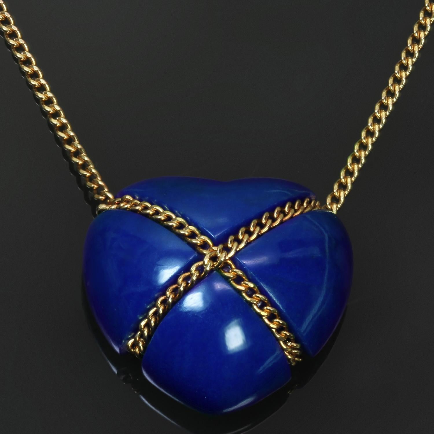 This stunning vintage necklace features a blue heart-shaped pendant crafted in lapis lazuli accented with a cross-over chain crafted in 18k yellow gold. Made in United States circa 1990s. Measurements: 0.55