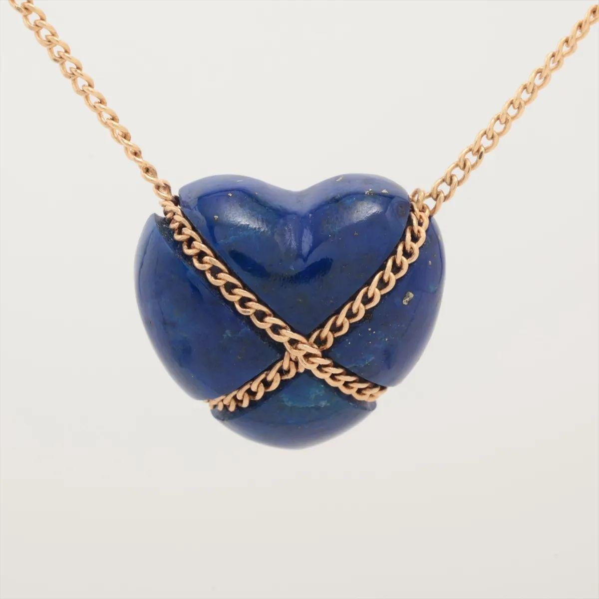 The Tiffany & Co. Lapis Lazuli Chain Crossover Heart Necklace showcases a delicate heart motif pendant crafted in yellow gold, gracefully intertwined with a vibrant lapis lazuli gem. The rich blue stone adds a striking contrast and depth to the