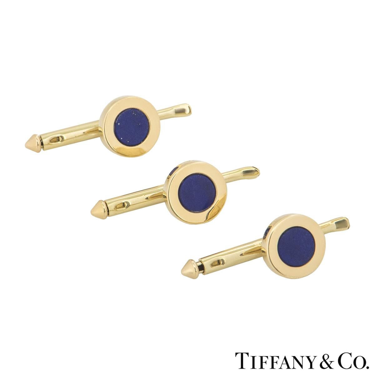 A 14k yellow gold Tiffany & Co. lapis lazuli pair of cufflinks and dress studs set. The pair of cufflinks feature 2 lapis lazuli discs set with a bar spacer with three similarly designed dress studs also set with lapis lazuli discs. The cufflinks