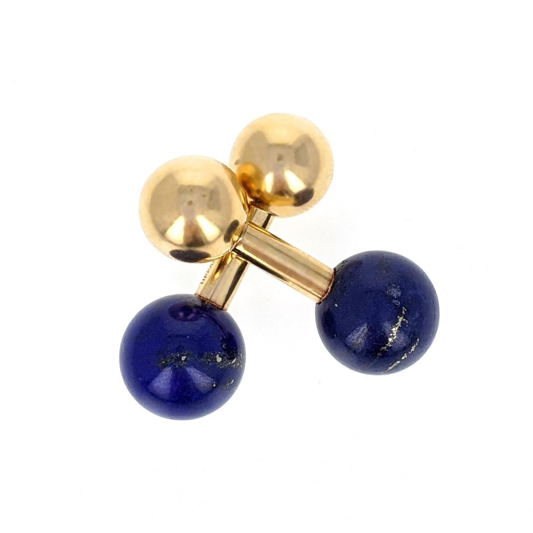 This elegant pair of cufflinks by Tiffany & Company features two round lapis lazuli stones and is mounted in 14 karat yellow gold. Each measures 1.13 inches long and the lapis lazuli measures approximately 11mm in diameter. Each is marked Tiffany &