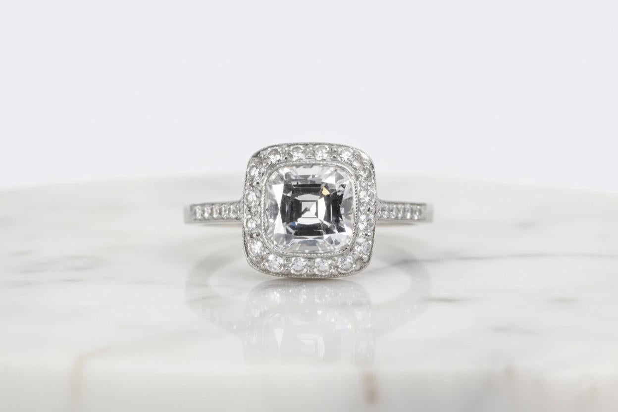 Cette exquise pièce de Tiffany & Co. La bague de fiançailles Legacy est ornée d'un diamant coussin brillant modifié de 1,70 carat, de couleur E et de pureté VS1 exceptionnelles. Encadrée d'un délicat halo de diamants ronds de taille brillant
