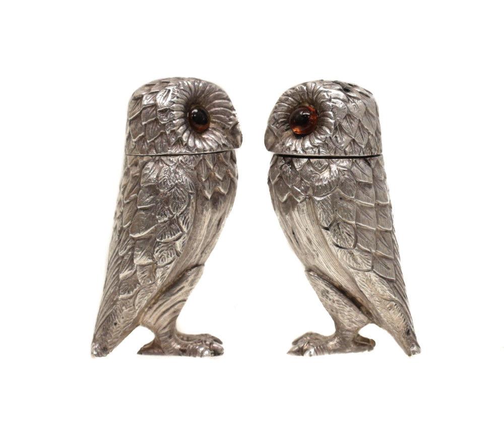 A gorgeous pair of Tiffany & Co. London sterling silver salt and pepper shakers in owl form, 1966. Beautiful hand chased feathers to the figural owls. Orange glass eyes. Hallmarks to the ends of the tail and marked Tiffany to the feet. 

Weight