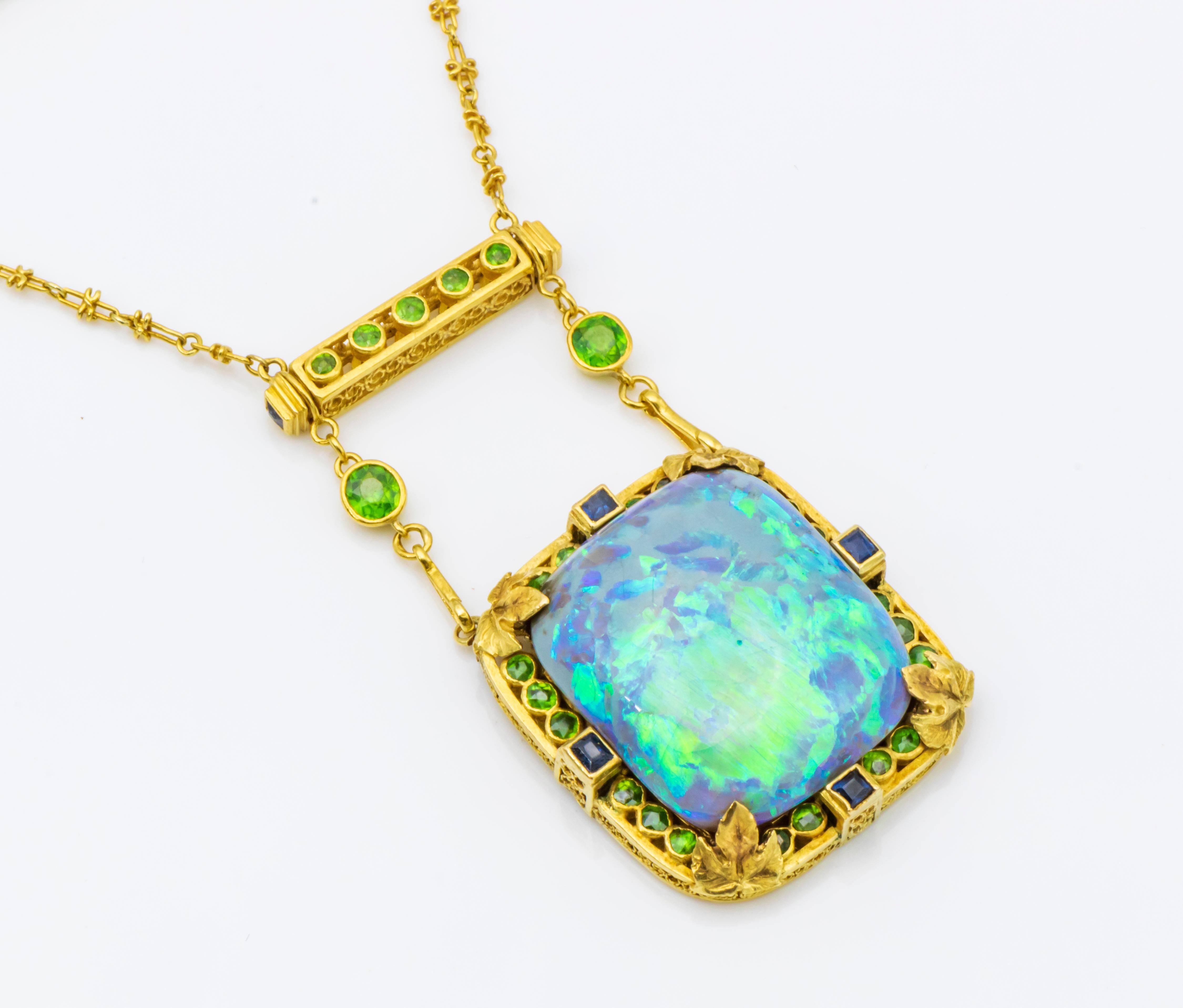 A black opal demantoid garnet and sapphire pendant brooch set with rectangular cushion-cut black opal tablet surrounded by bezel set demantoid garnets and sapphires accented by grape leaves, suspending from a removable delicate link chain accented