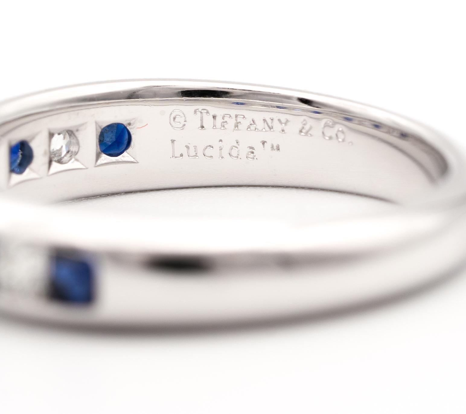 Tiffany & Co. Sapphire and Diamond Ring finely crafted in platinum channel set with seven rectangular cut sapphires , fine deep blue color weighing approximately 0.45 carats and six cushion cut diamonds weighing approximately 0.40 carats halfway