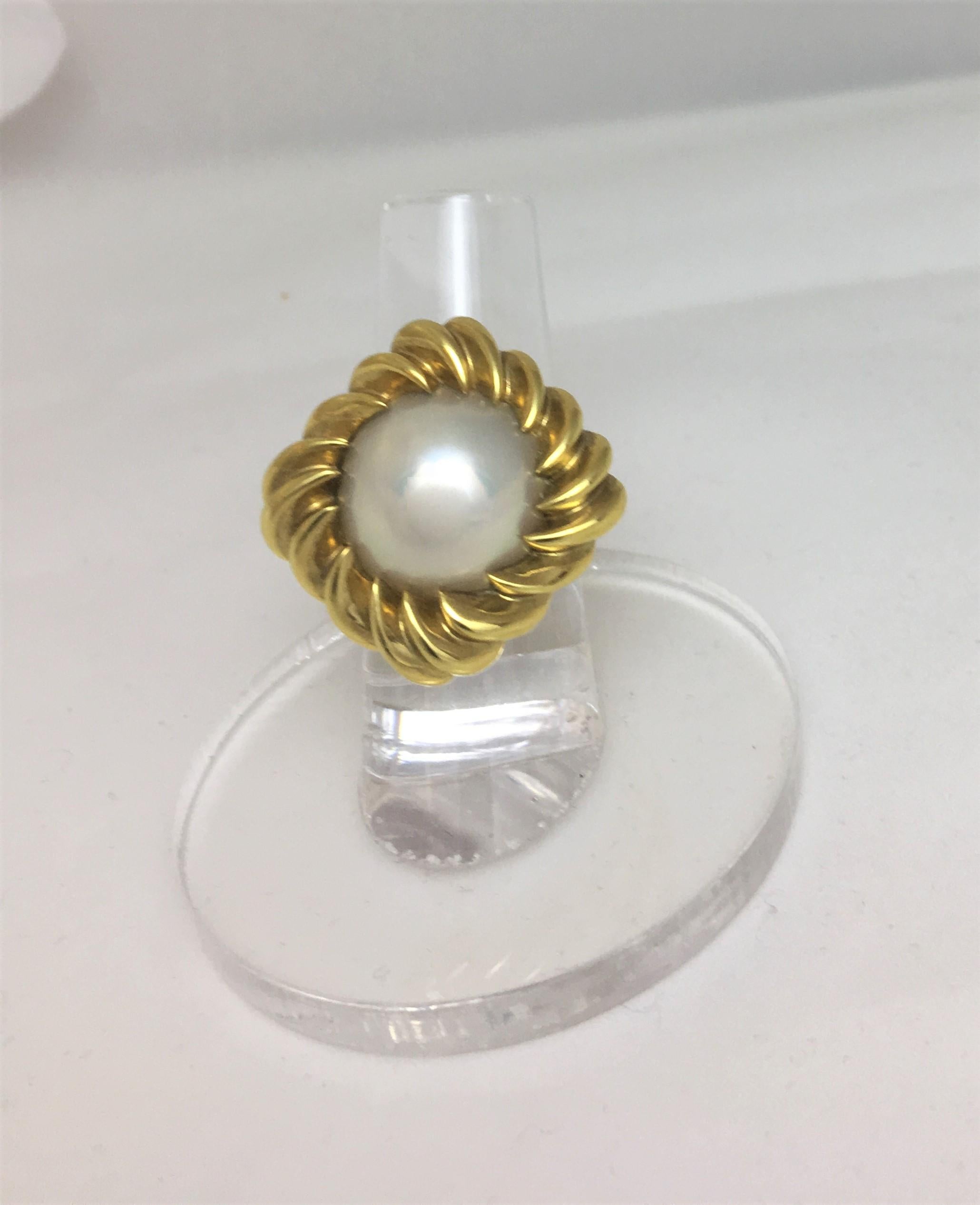Tiffany & Co.
18K yellow gold ribbed design mounting in square cushion shape on top (square with rounded corners)
Cushion part of mounting measures approximately 1.75 Inches
White Mabe pearl with creamy tones, approximately 1.25mm round
Stamped 