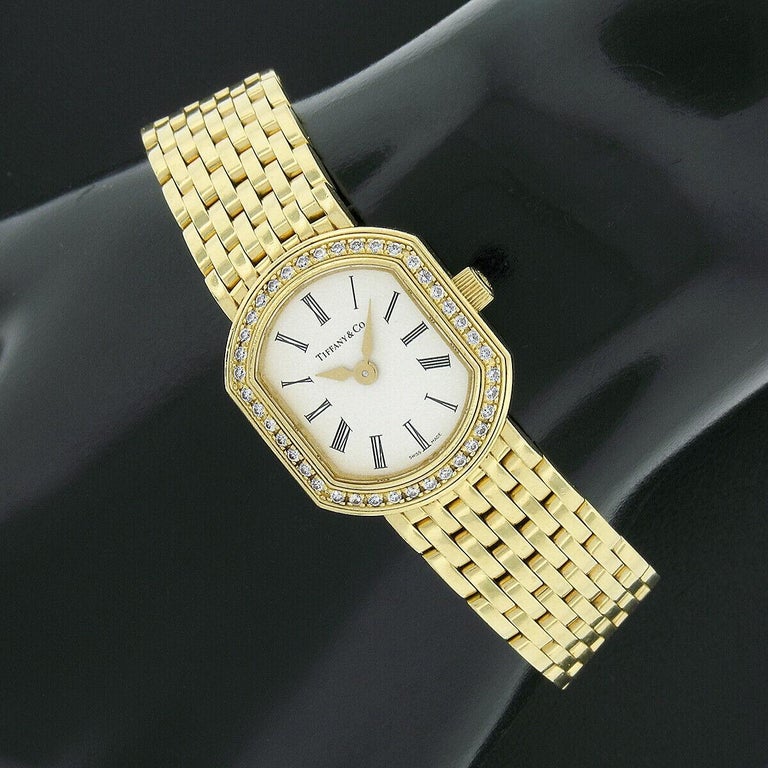 This elegant and well-made ladies' Tiffany & Co. Resonator wrist watch by Mark Coupe features a 21mm solid 18k yellow gold cushion shaped case decorated with an outstandingly fine quality diamond bezel throughout. The diamonds bezel consisting of 40