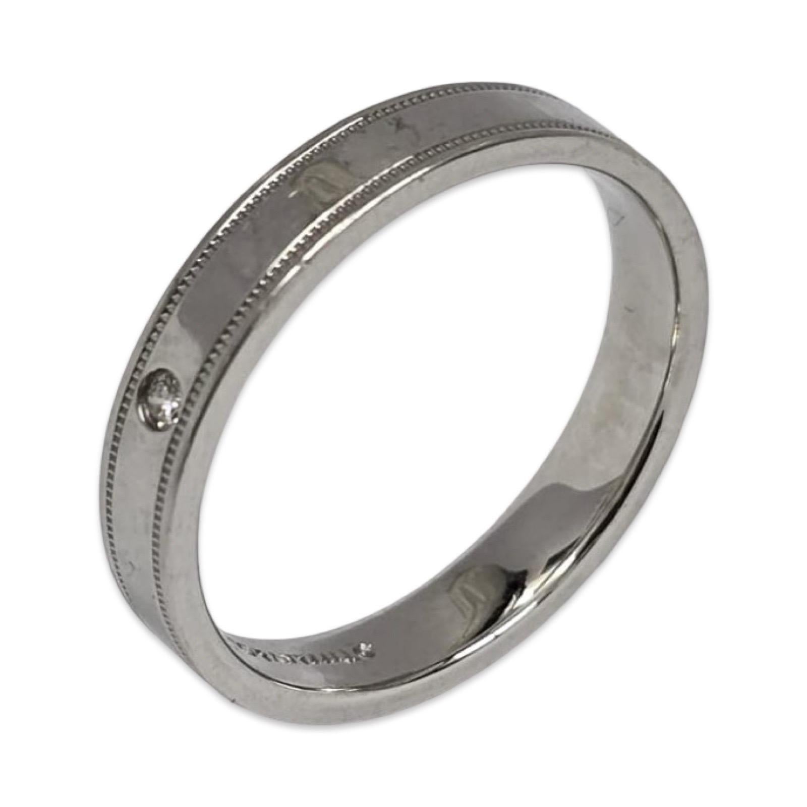 Intemporelle et raffinée, cette alliance pour homme de Tiffany & Co. est réalisée en platine massif et pèse 7,5 grammes. Le modèle est orné d'un seul diamant rond brillant serti à fleur de peau et de détails milgrain classiques sur les bords. Une