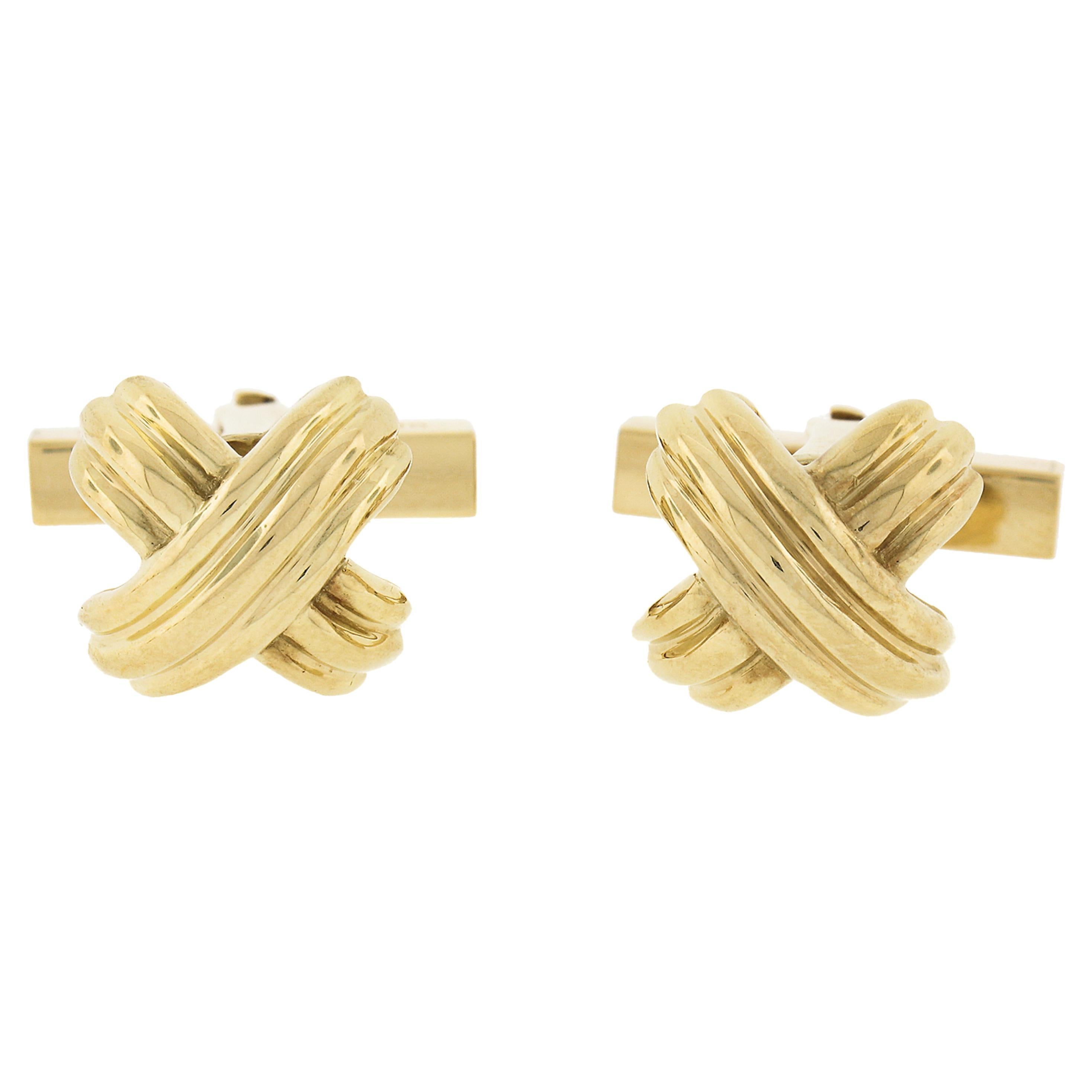 Here we have an authentic Tiffany & Co. classy set of solid 18k yellow gold cuff links and 4 button studs. All of the panels are X signature shaped and feature a grooved sharp-looking with polished finish throughout. The swivel backings of the cuff