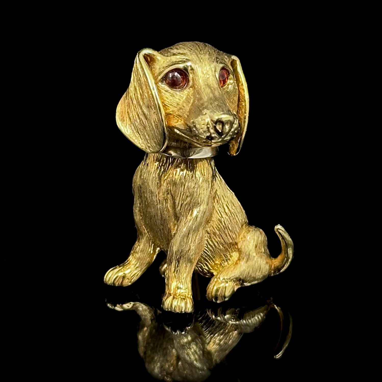 Tiffany & Co. Mid-Century Garnet Dachshund Dog Brooch in Yellow Gold, circa 1960. Modelled as a sitting dachshund dog with a raised tail, the canine is beautifully crafted in yellow gold with a realistically carved Florentine finishing depicting its