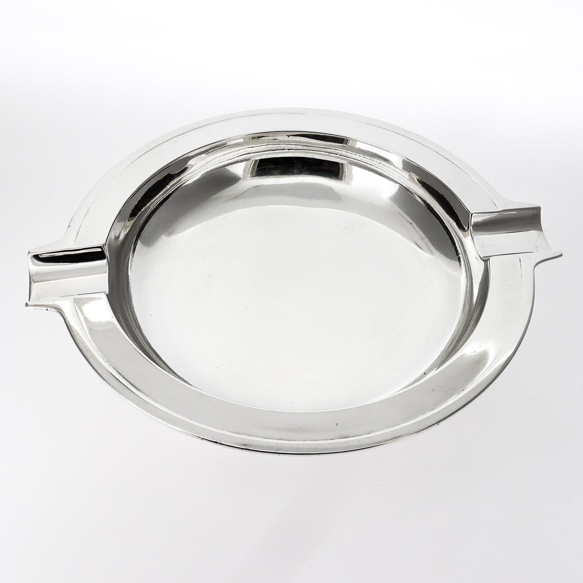 Un bel posacenere d'argento firmato Machine Age. 

Da Tiffany & Co.

In argento sterling.

Di forma circolare, con una coppia di ampi poggia sigari o sigarette ai lati e un bacino incassato.

Completamente marcato alla base.

Un design Tiffany