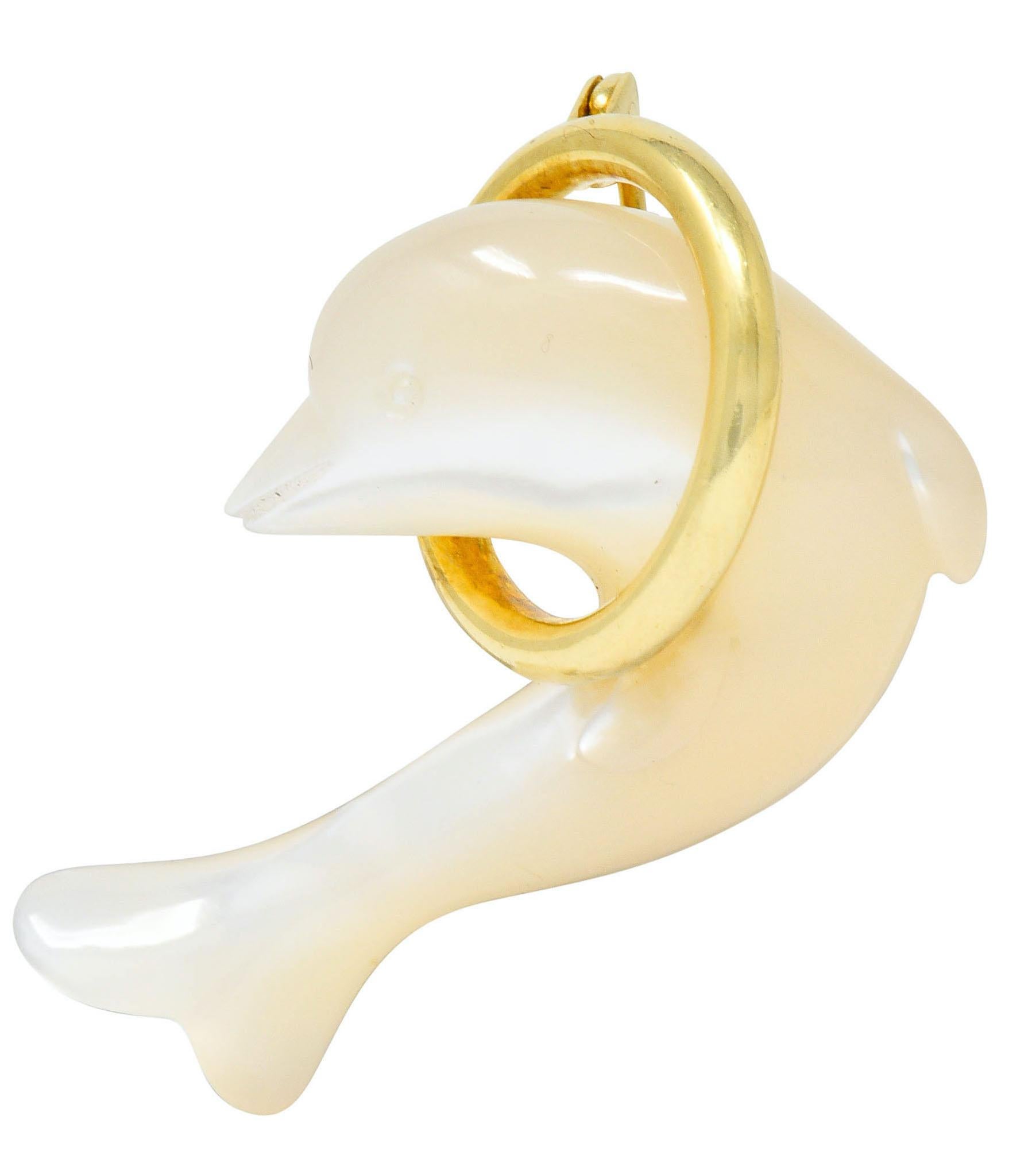 Brooch is designed as a mother-of-pearl dolphin jumping through a polished gold hoop

Dolphin has carved details and is white to cream in color with strong iridescence in some areas

Completed by pin stem and locking closure

Signed T & Co. for