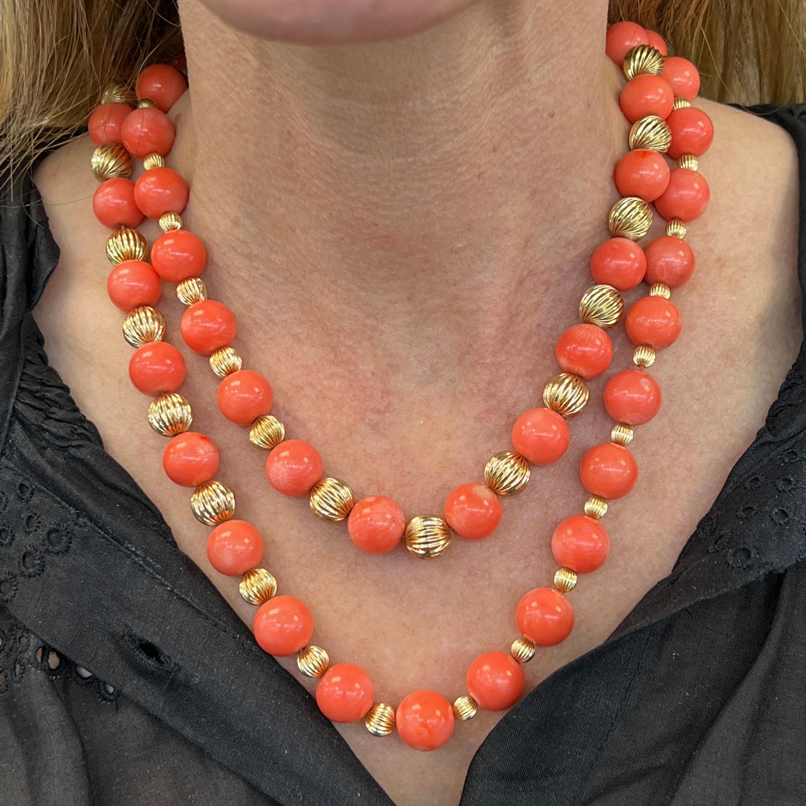 Rare large coral bead estate necklace designed by Tiffany & Company. The necklace features natural coral beads measuring 12.5mm in size, and ribbed 14 karat yellow gold balls. The X clasp is a Tiffany hallmark, and the necklace measures 40 inches in