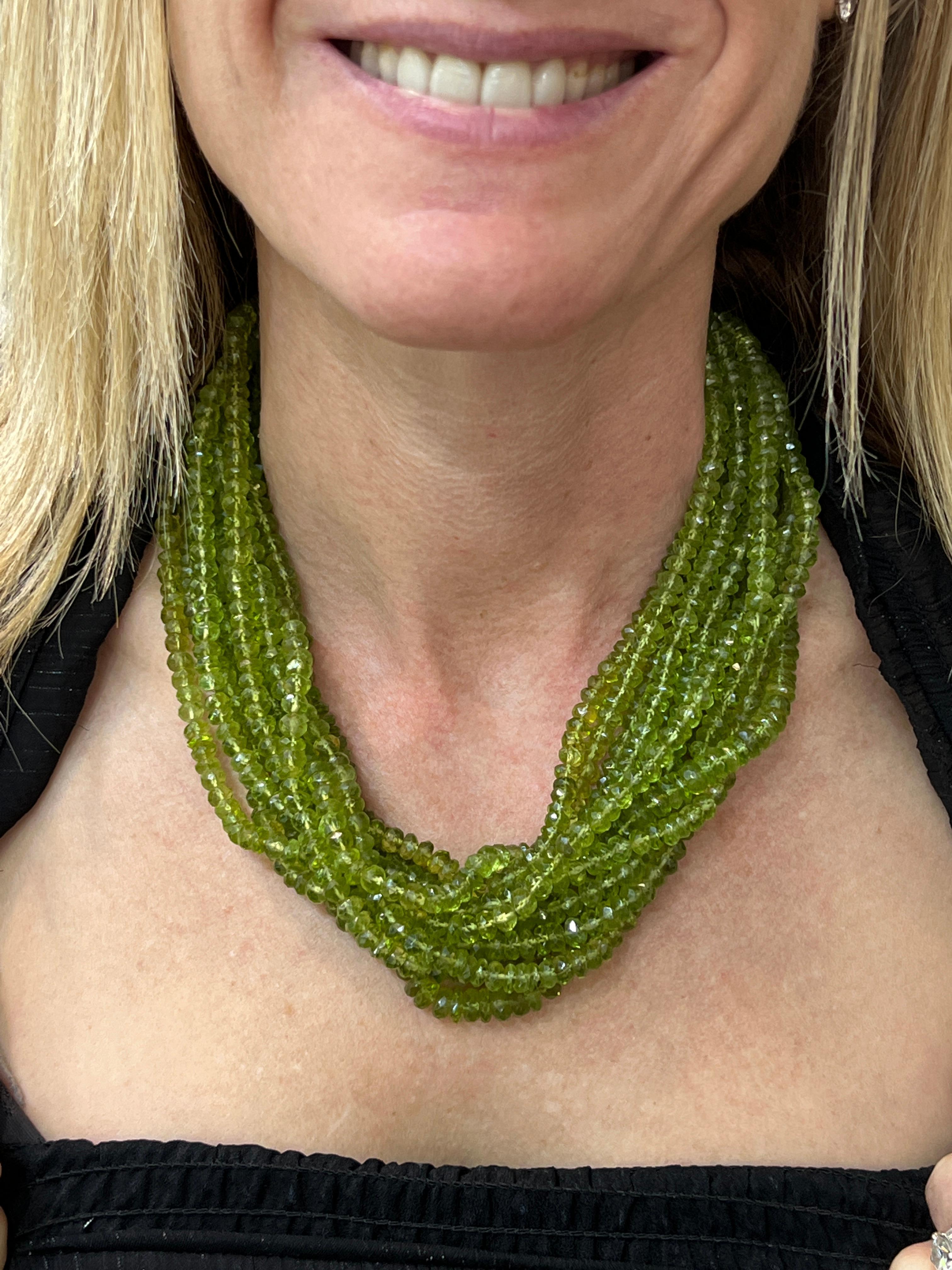Rare vintage peridot bead necklace by  designer Tiffany  & Co. The vintage necklace features 12 strands of natural green peridot gemstones with an 18 karat white gold and diamond clasp. The clasp is set with 30 round brilliant cut diamonds weighing