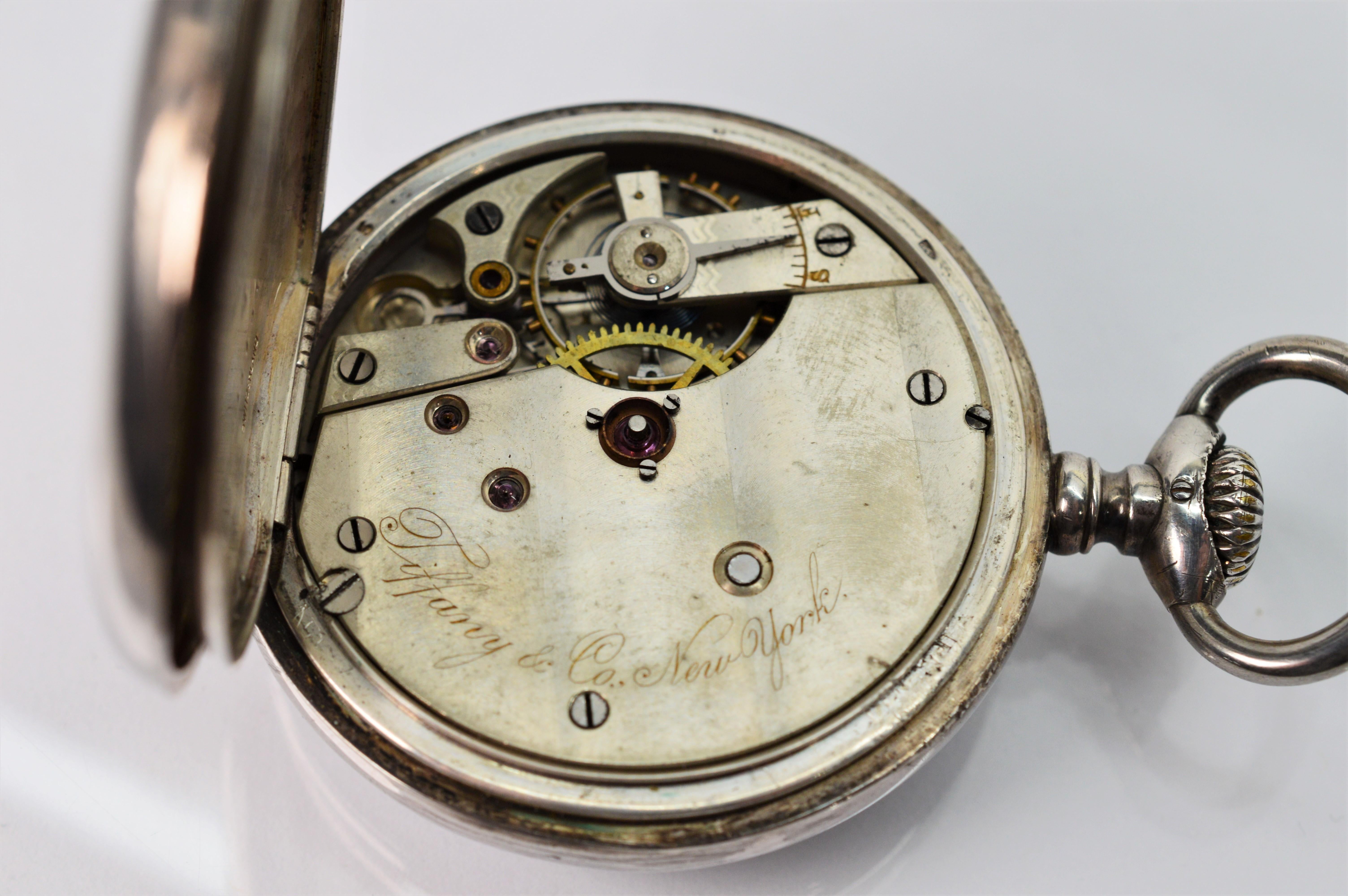 Authentic Tiffany & Co. New York .935 Sterling Silver Men's Pocket Watch, circa 1900 to 1920. Size 47 mm. Hunter Case number 493051.
This collector piece has a porcelain face with Arabic numerals and has outer 5 minute incremental scale. Slight wear