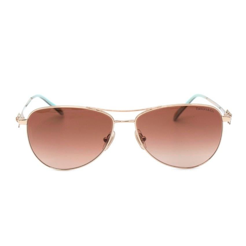 Tiffany & Co. Pale Gold Ribbon Temple Aviator Sunglasses
 

 - Aviator style sunglasses
 - Metal frame finished with Tiffany & Co bow decoration on the arms
 - Tonal brown lenses
 

 Materials:
 Stainless Steel
 

 Made in Italy
 

 PLEASE NOTE,