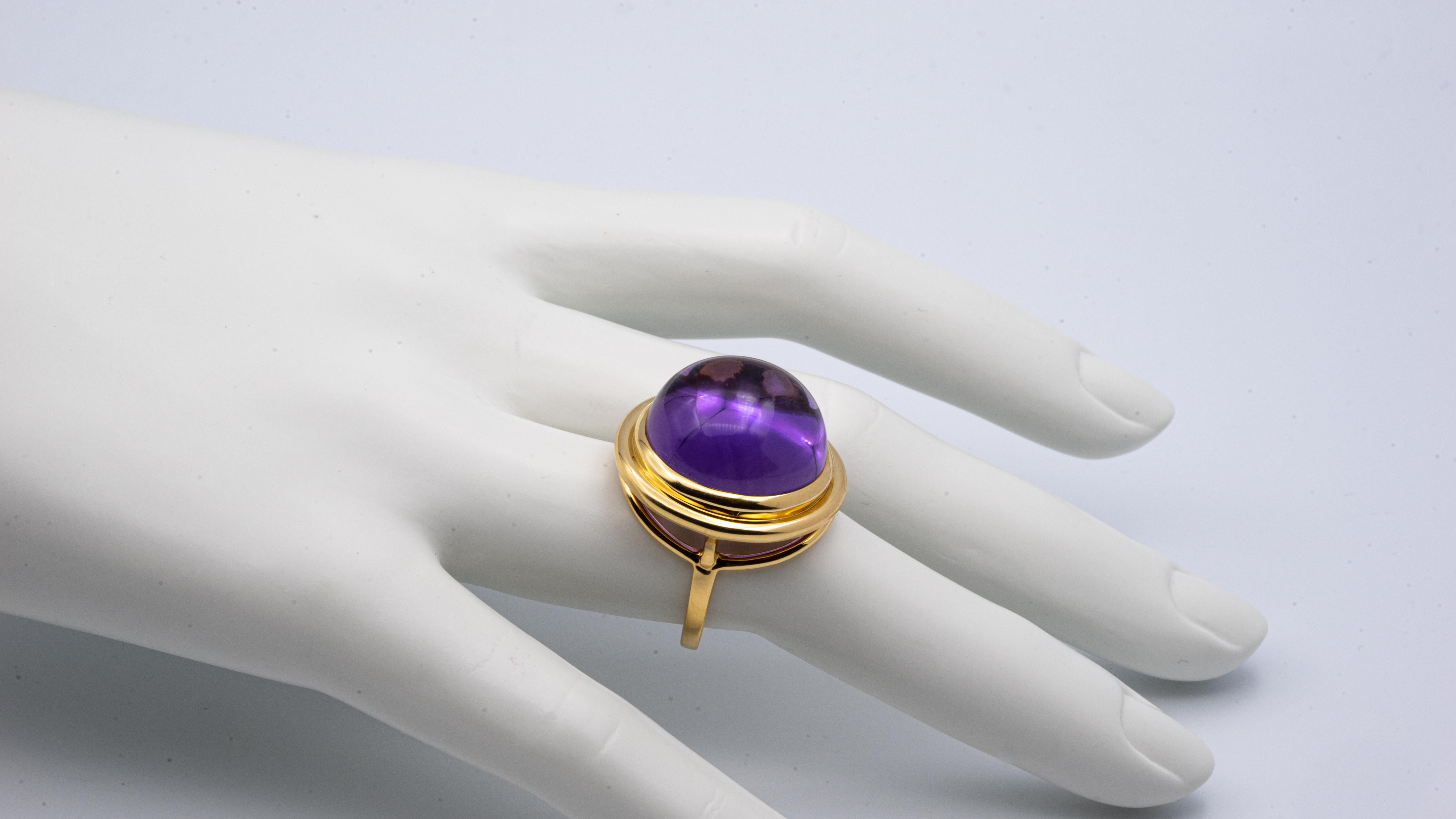 Tiffany & Co. Paloma Picasso ring finely crafted in 18 karat yellow gold with one round cabochon deep purple amethyst weighing approximately 26.00 cts., 
With signed box. 
Hallmarks: Signed T & Co., Paloma Picasso, 
Weight: 9.5 dwts. 
Size 6 1/2,